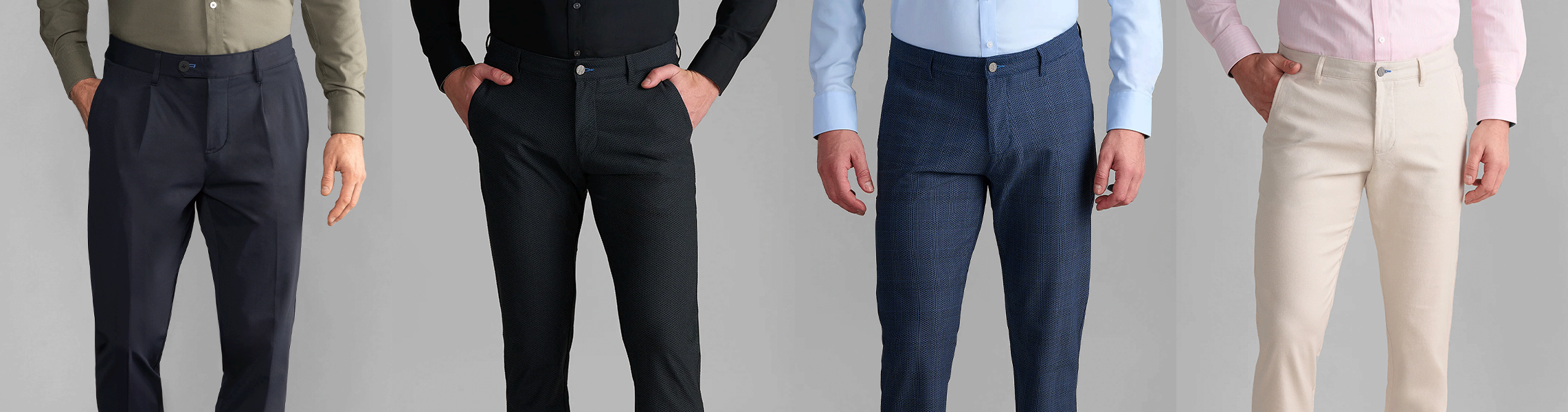 Four men stand side by side, each wearing dress pants in different colors: dark gray, black, blue plaid, and beige, paired with shirts in olive, black, light blue, and pink. Their faces are not visible.