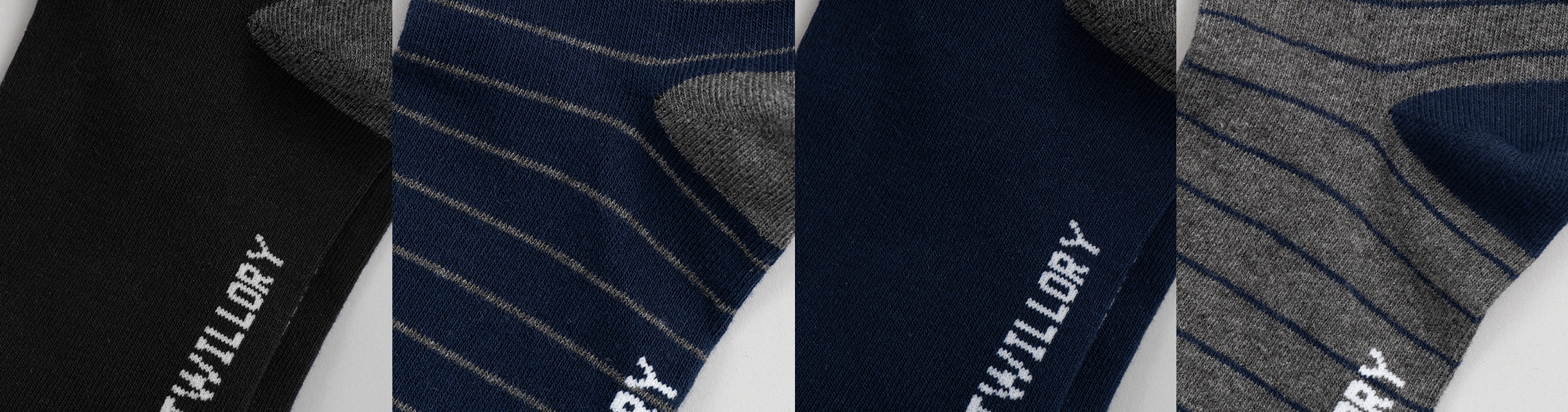Close-up of four socks in a row: solid black, navy with gray stripes, solid navy, and solid gray with navy accents. Each sock has white WILDRY text at the toe.