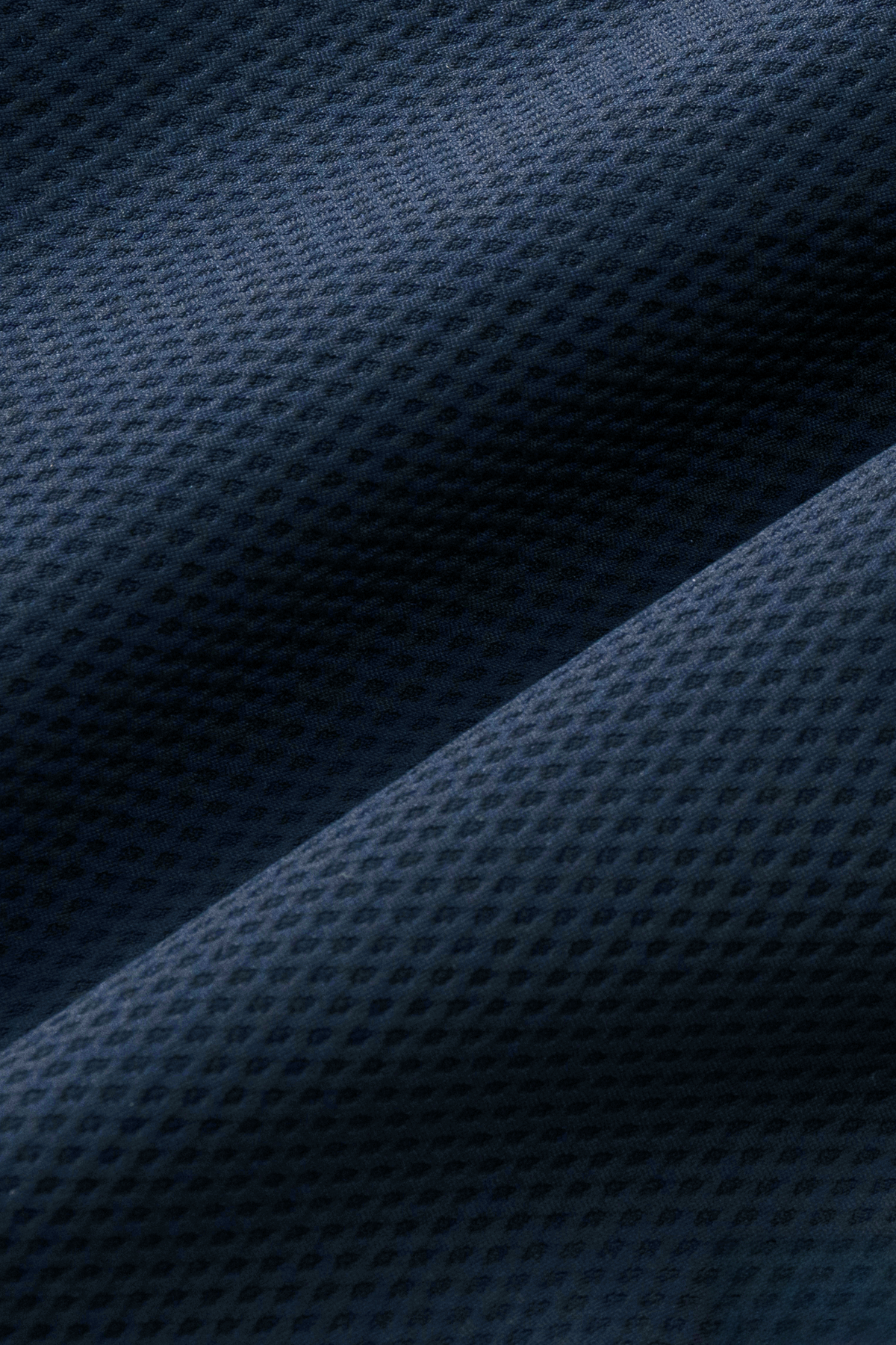 Close-up of Twillory's AIR Resort Shirt Solid in Navy shows its dark blue, perforated fabric with a subtle grid pattern. Soft folds highlight the shirt’s flexible, breathable feel and 4-way stretch for ultimate comfort.