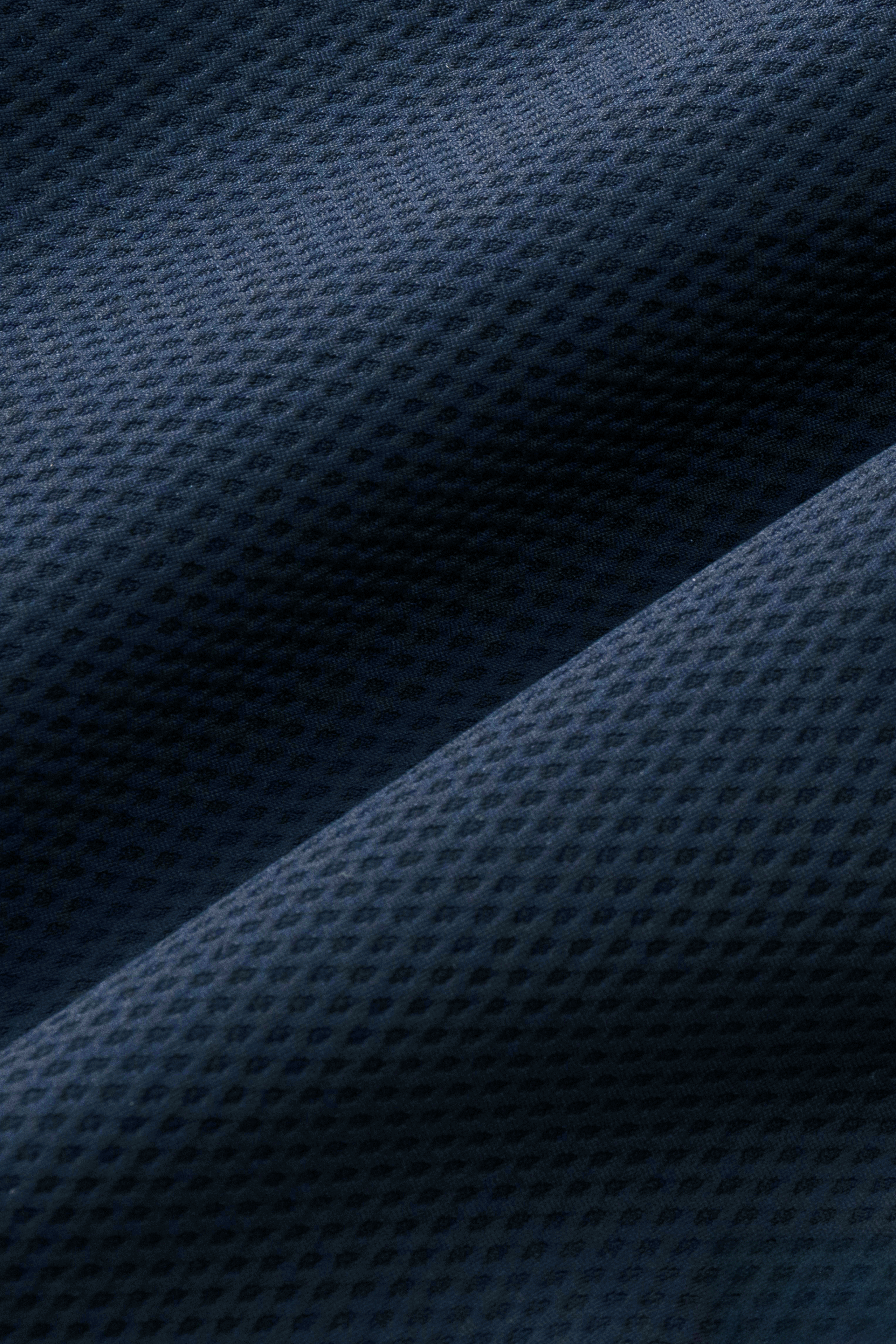 Close-up of Twillory's AIR Resort Shirt Solid in Navy shows its dark blue, perforated fabric with a subtle grid pattern. Soft folds highlight the shirt’s flexible, breathable feel and 4-way stretch for ultimate comfort.