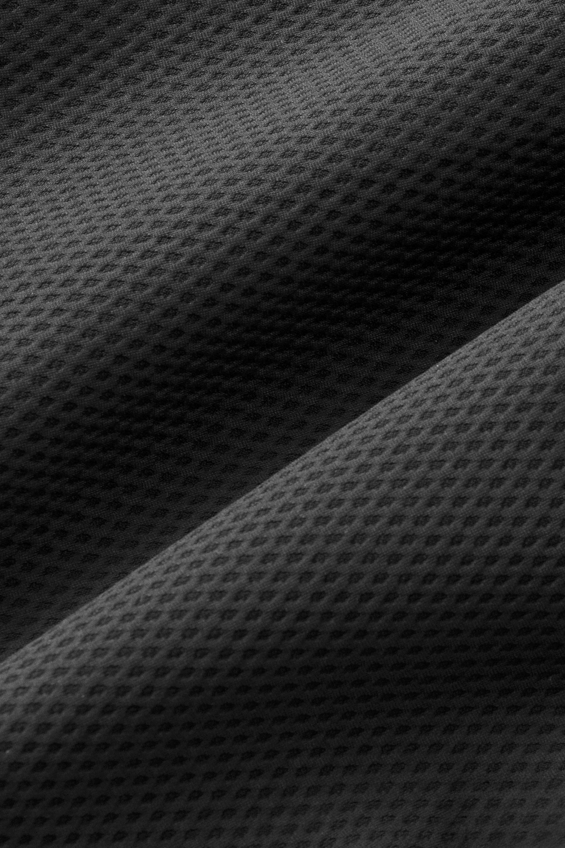 Close-up of heather light grey textured stretch fabric from Twillory's AIR Pants, folded to showcase soft shadows and highlights that accentuate the 360° Airflow mesh-like surface and subtle sheen.