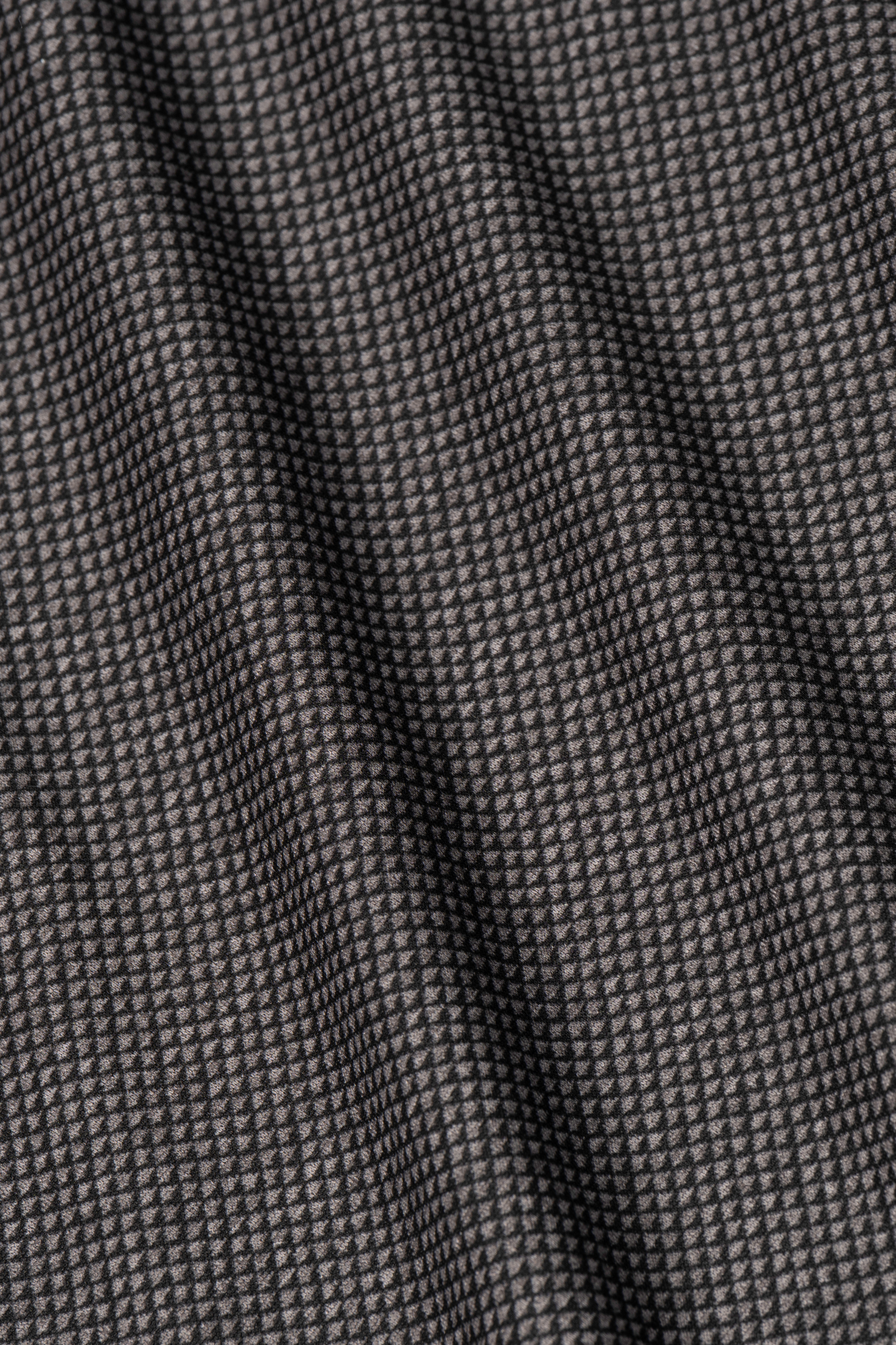Close-up of Twillory's Long Sleeve Button Down Polo Dot // Grey Scale fabric, featuring a black and gray geometric dot pattern. Slightly wrinkled texture creates diagonal folds and shadows, emphasizing the subtle grid design.
