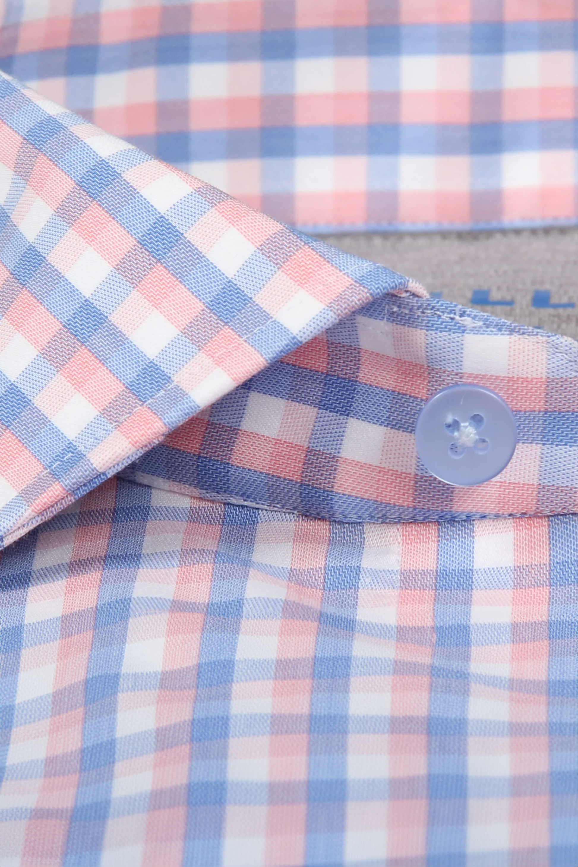 Close-up of Twillory’s Leader Check // Orange Blue performance shirt, showcasing its orange and blue plaid, 4-way stretch fabric, moisture wicking, and details like a crisp collar, blue button, and neat buttonhole stitching.