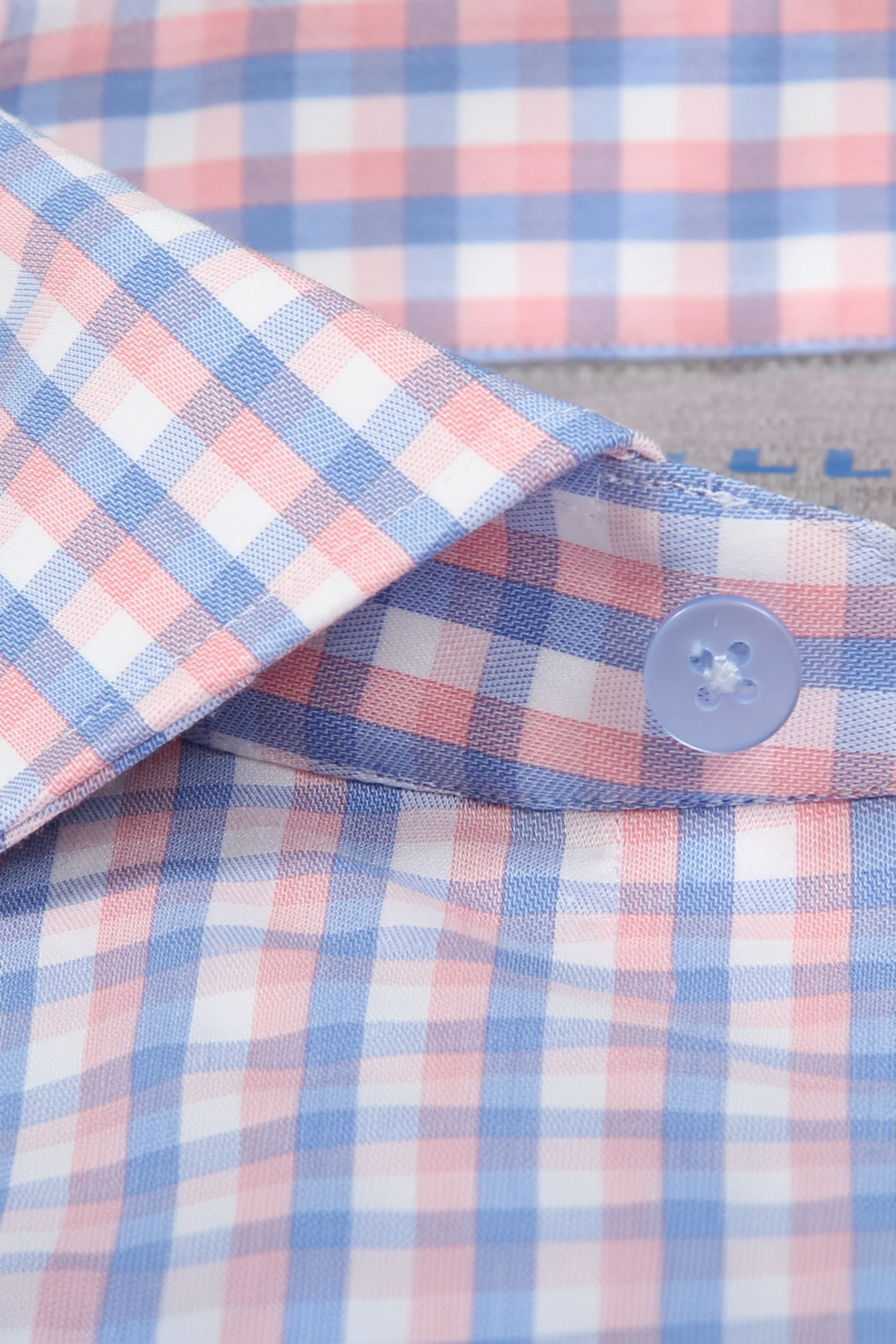 Close-up of Twillory’s Leader Check // Orange Blue performance shirt, showcasing its orange and blue plaid, 4-way stretch fabric, moisture wicking, and details like a crisp collar, blue button, and neat buttonhole stitching.