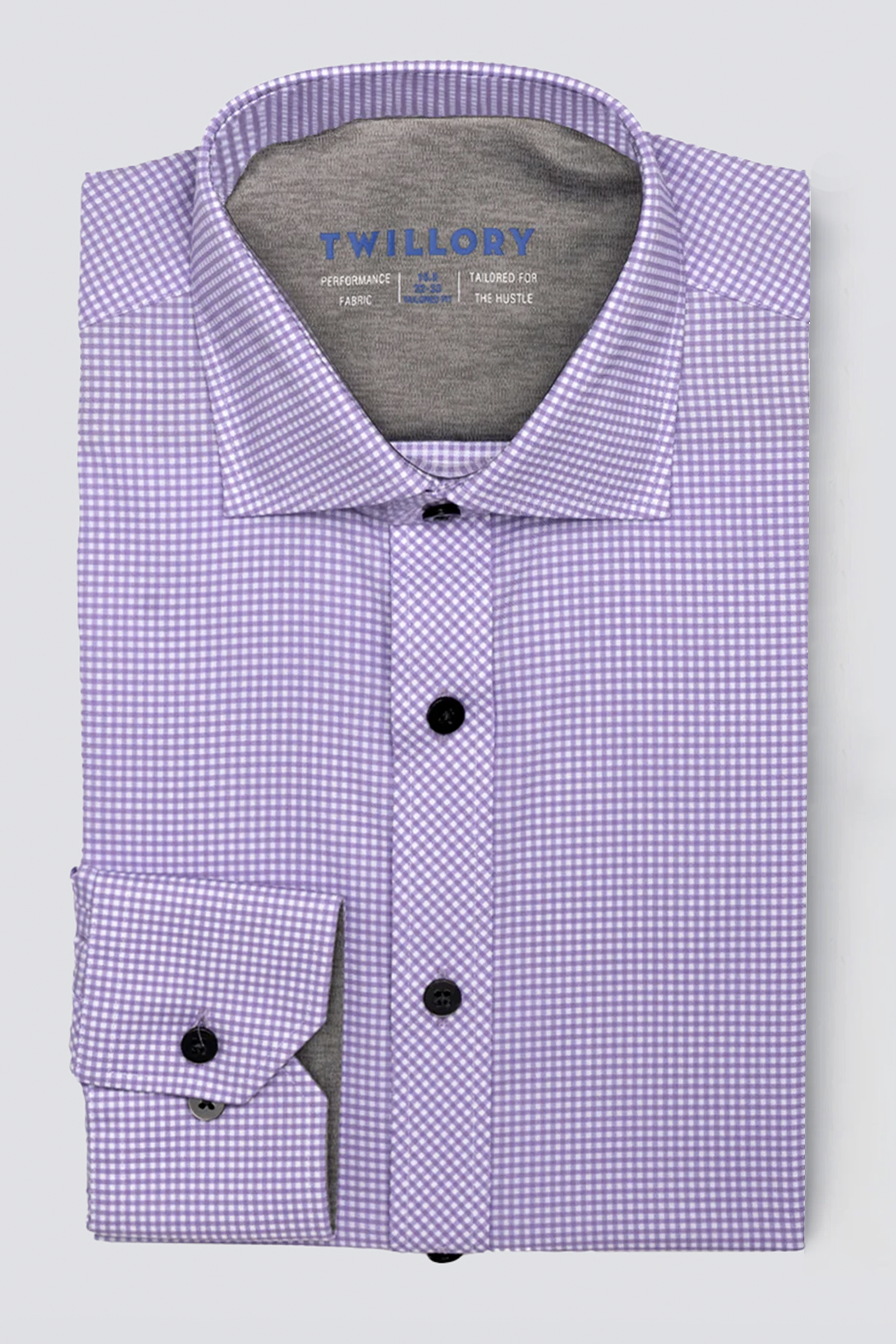 The Twillory Leader Check // Lavender is a folded long-sleeve performance shirt in a purple and white check pattern with black buttons, spread collar, visible left cuff, printed sizing details inside the collar, and 4-way stretch for comfort.