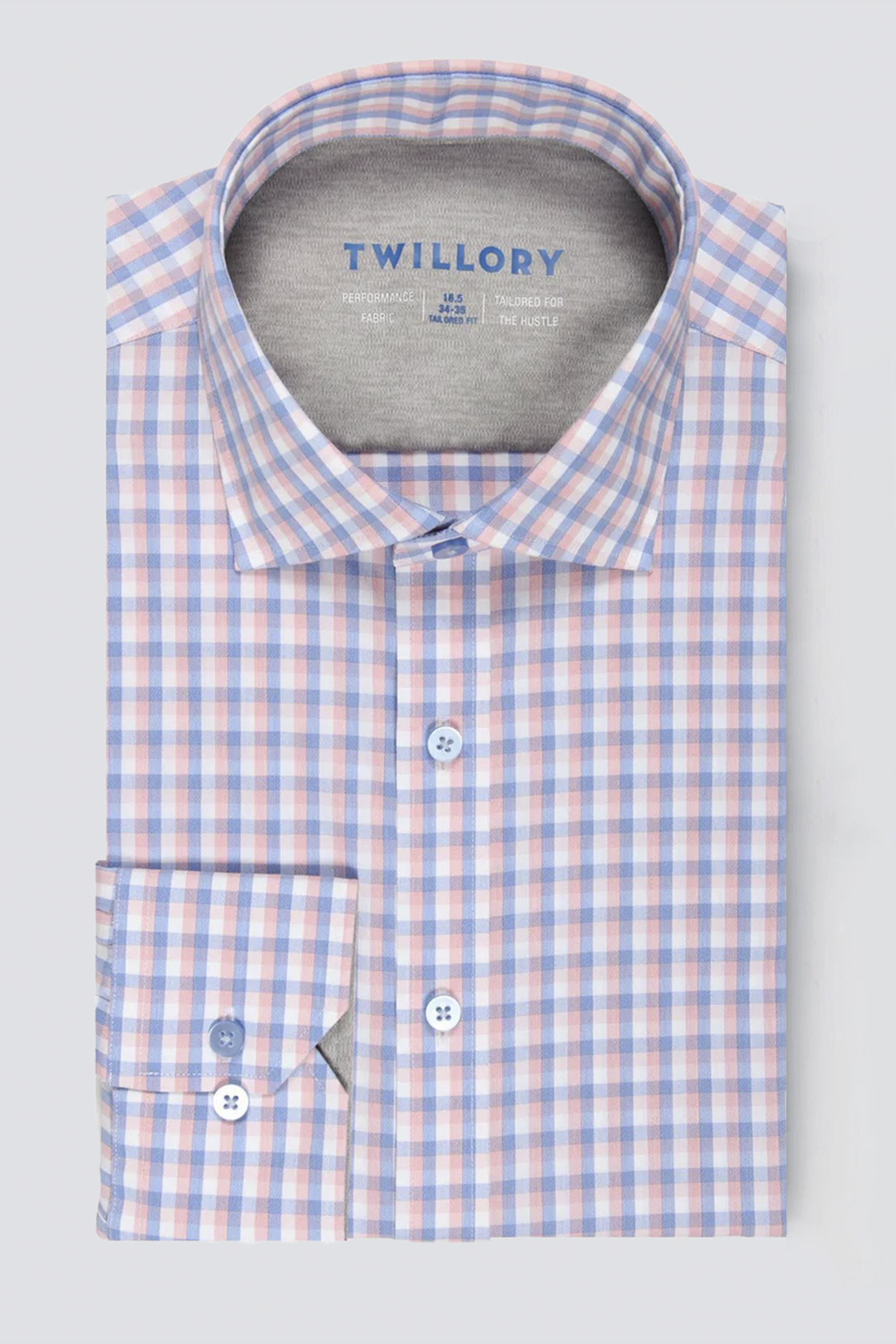 A neatly folded Twillory performance shirt, Leader Check // Orange Blue, features a blue, orange, and white checkered pattern, crisp collar with “Twillory” inside, two-button cuffs, and moisture-wicking fabric for all-day comfort.