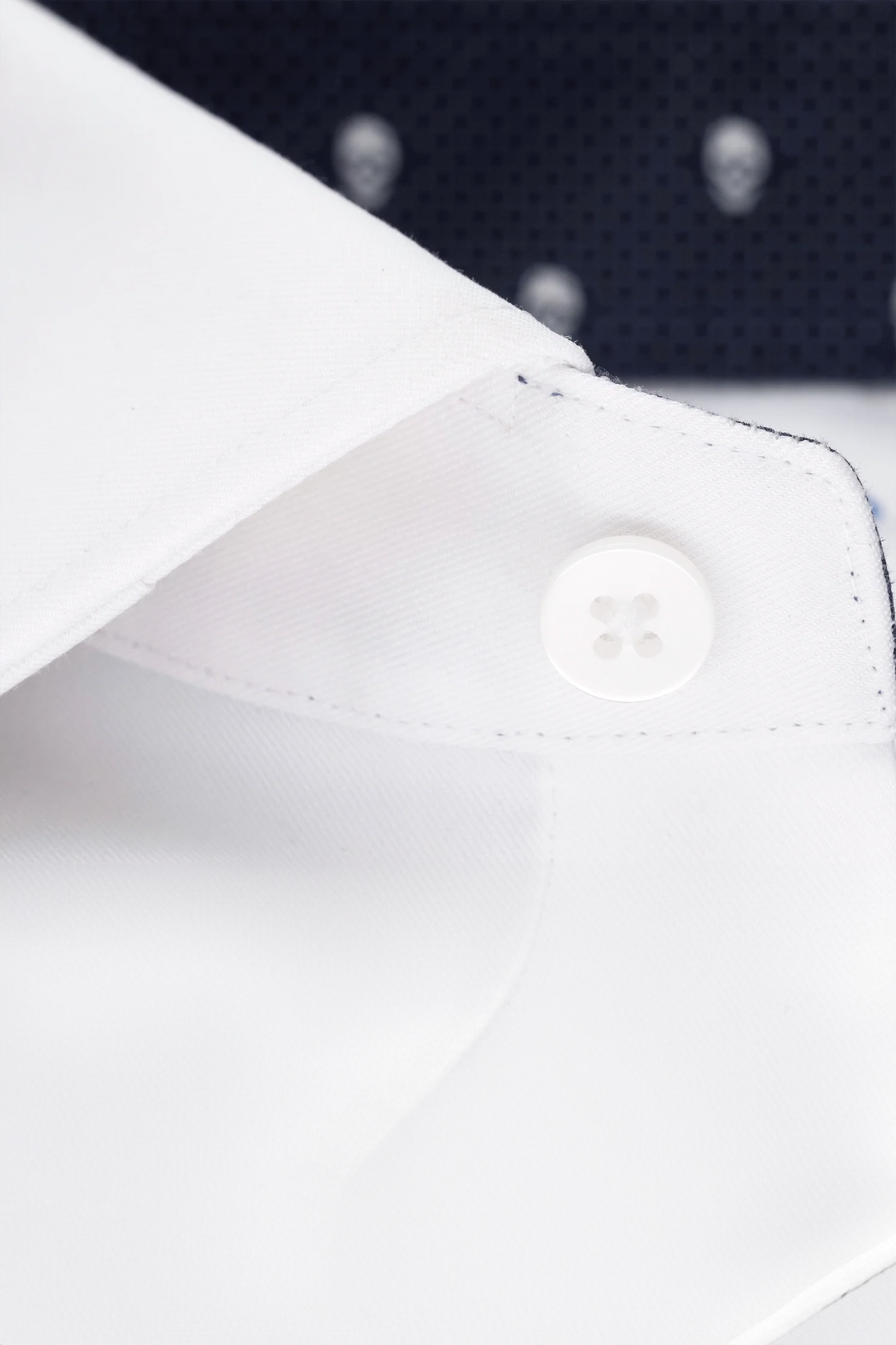 Close-up of a Twillory Leader Contrast // Navy Skull shirt: crisp white collar with fine stitching and button, paired with navy fabric featuring small white skulls. Offers a sharp, elegant style and 4-way stretch comfort.
