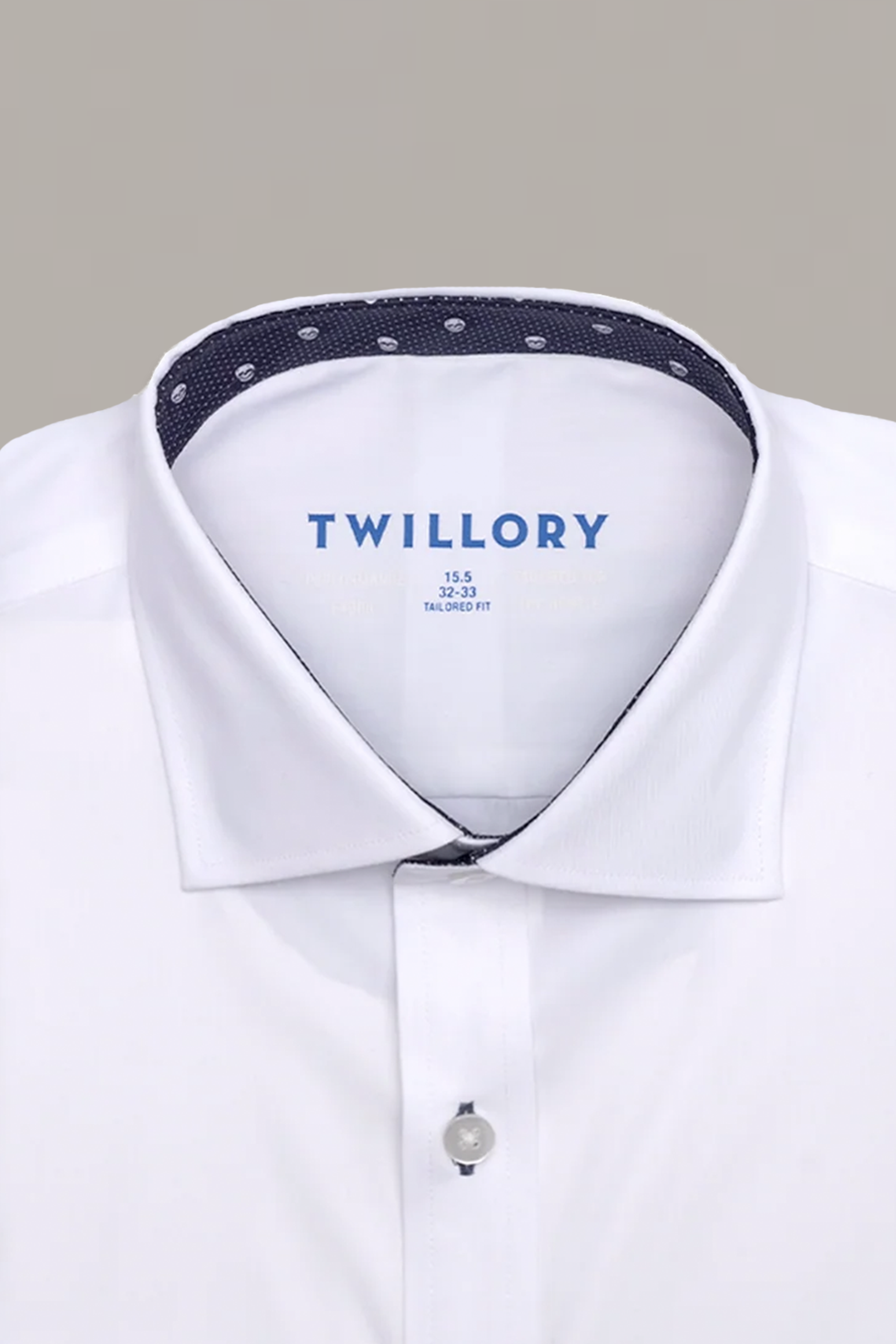 A close-up of the Twillory Leader Contrast // Navy Skull Performance Shirt shows its crisp white fabric, buttoned collar, and a navy lining with white dots inside. “Twillory” and sizing details are printed in blue. The background is light gray.
