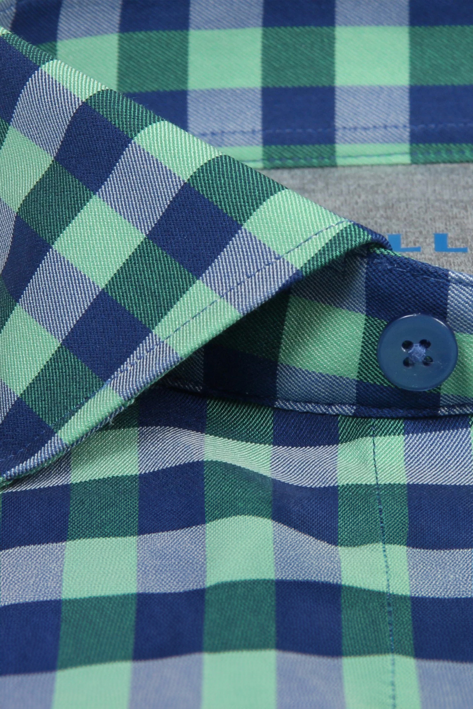 Close-up of the Twillory Leader Gingham // Green Blue shirt collar, featuring blue, navy, and green plaid fabric, a blue button on the placket, neat stitching, crisp construction, and moisture-wicking properties for comfort.