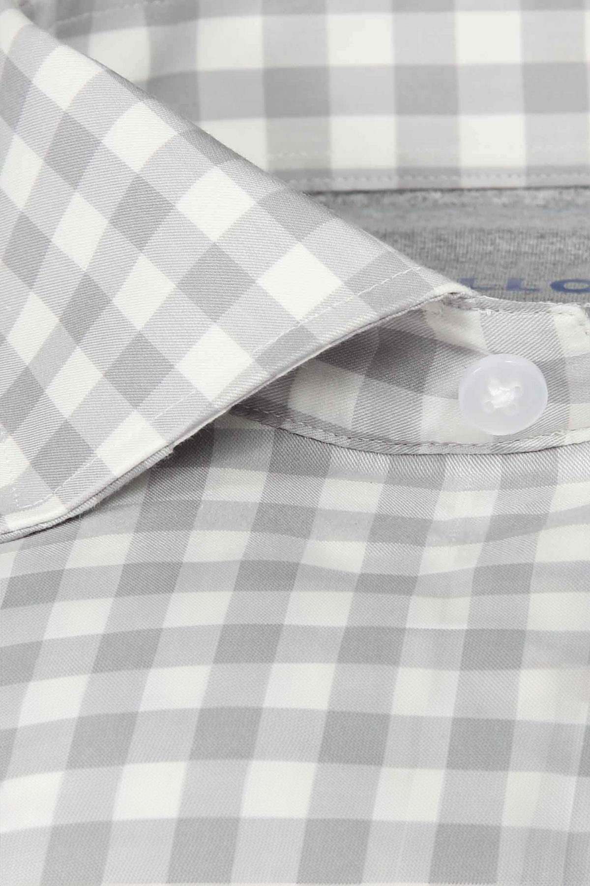 Close-up of the Twillory Leader Gingham // Grey White shirt collar, showcasing a light gray and white check. This performance shirt delivers 4-way stretch, moisture-wicking fabric for lasting comfort and a crisp, pressed look all day.