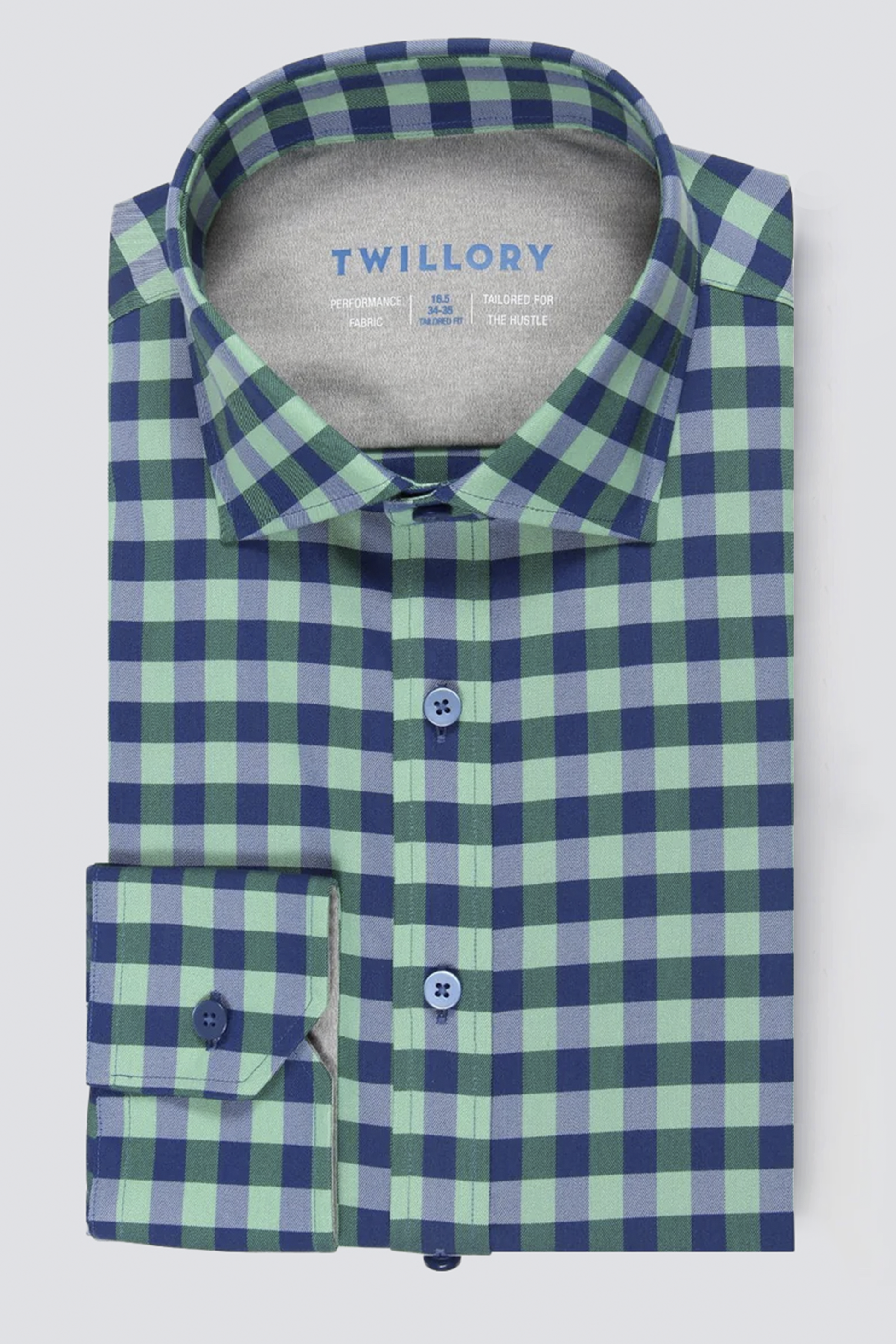 The Twillory Leader Gingham // Green Blue is a neatly folded long-sleeve shirt with a blue and green check pattern, blue buttons, and inner collar branding. Made from moisture-wicking fabric, it's shown against a light background.