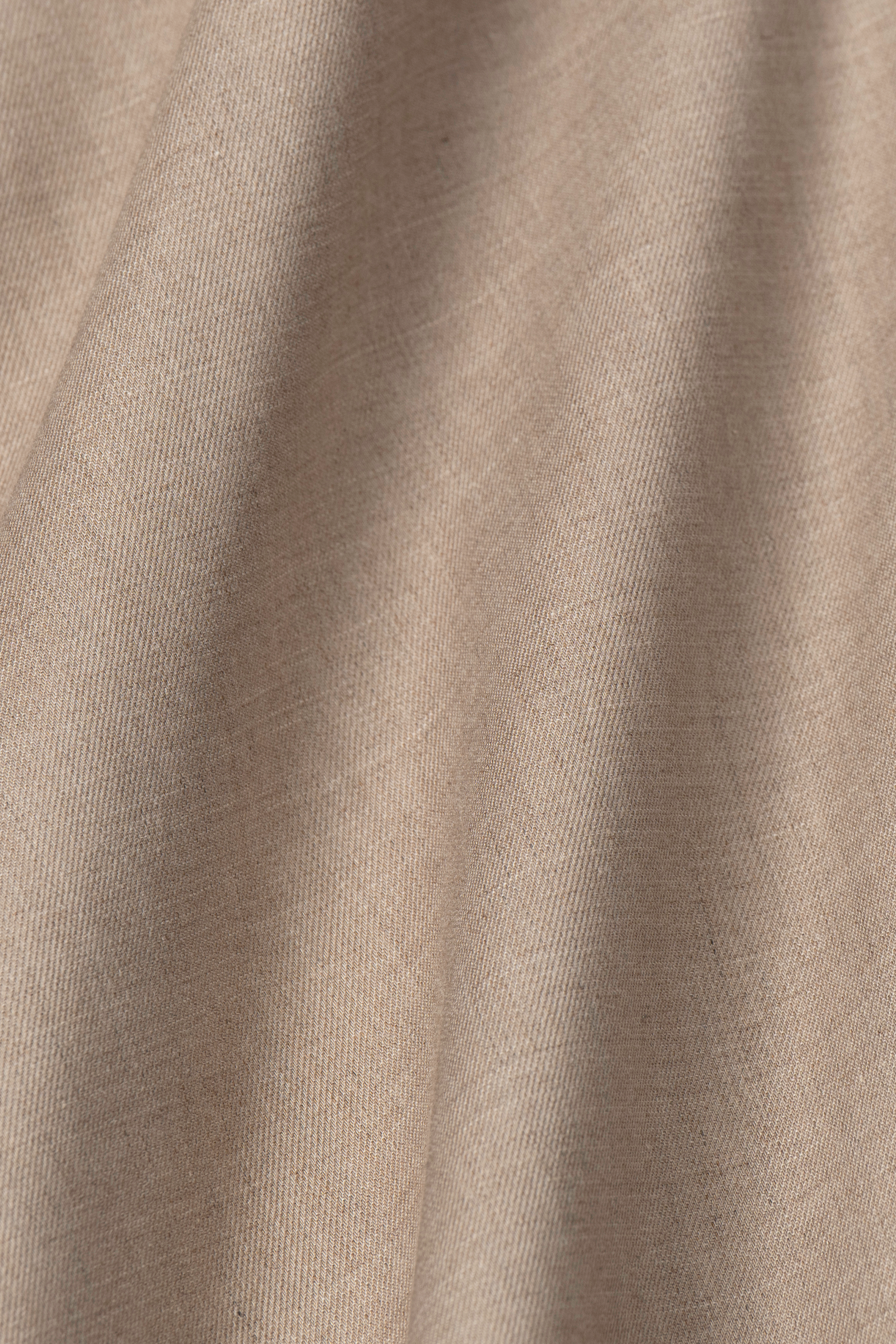 Close-up of Heather Sepia fabric by Twillory shows its light brown, textured weave with subtle folds. This soft, natural material offers moisture wicking—ideal for the Leader Solid performance shirt.