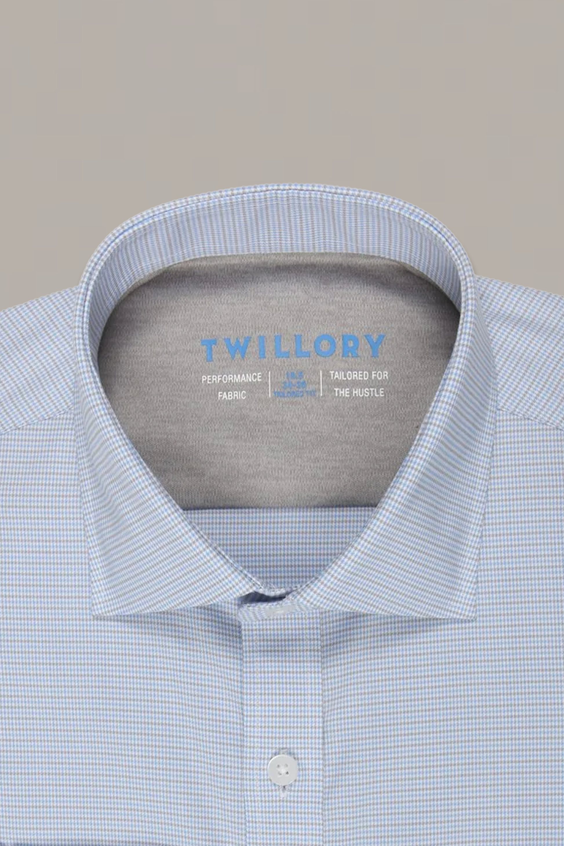 A neatly folded Twillory Leader Houndstooth // Grey Blue shirt shows the open collar with brand details inside, emphasizing its moisture-wicking and 4-way stretch performance features.