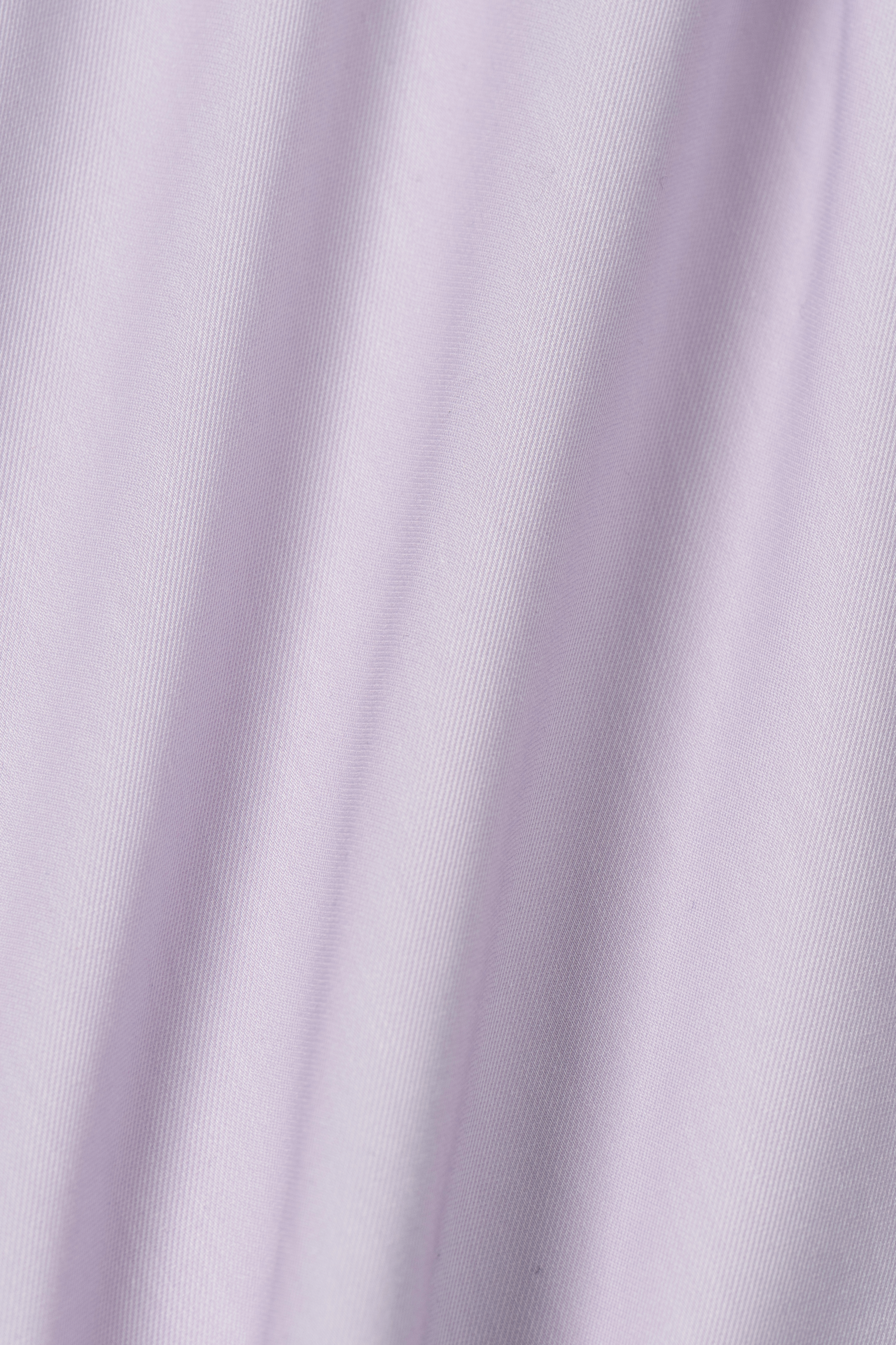 A close-up of Leader Solid // Lavender by Twillory shows pale lavender fabric with diagonal grooves and a smooth, slightly shiny texture—perfect for a performance shirt with moisture-wicking properties to keep you cool and comfortable.