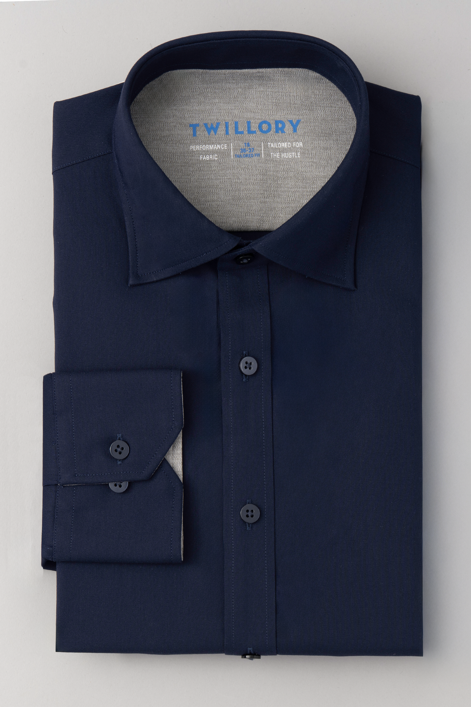 The Twillory Leader Solid // Navy is a neatly folded navy blue performance shirt with a stiff collar, French cuffs, and light gray inner collar and cuff lining. It features non-iron, 4-way stretch fabric, and the Twillory logo inside the collar.