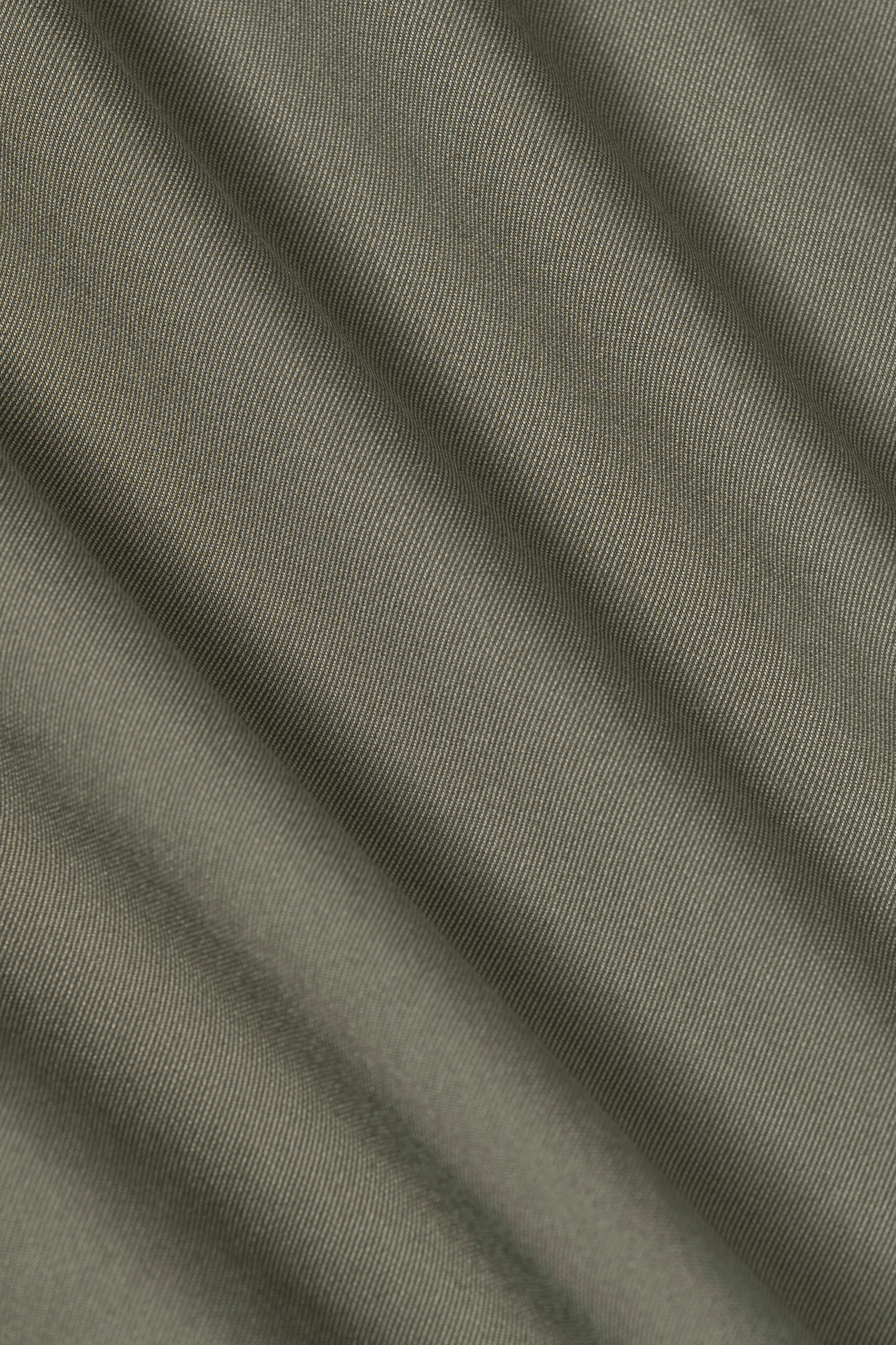 Close-up of Leader Solid // Olive by Twillory shows olive green fabric with diagonal ridges and fine texture, featuring gentle folds. The soft, tightly woven material offers 4-way stretch—perfect for a performance shirt with comfort and flexibility.