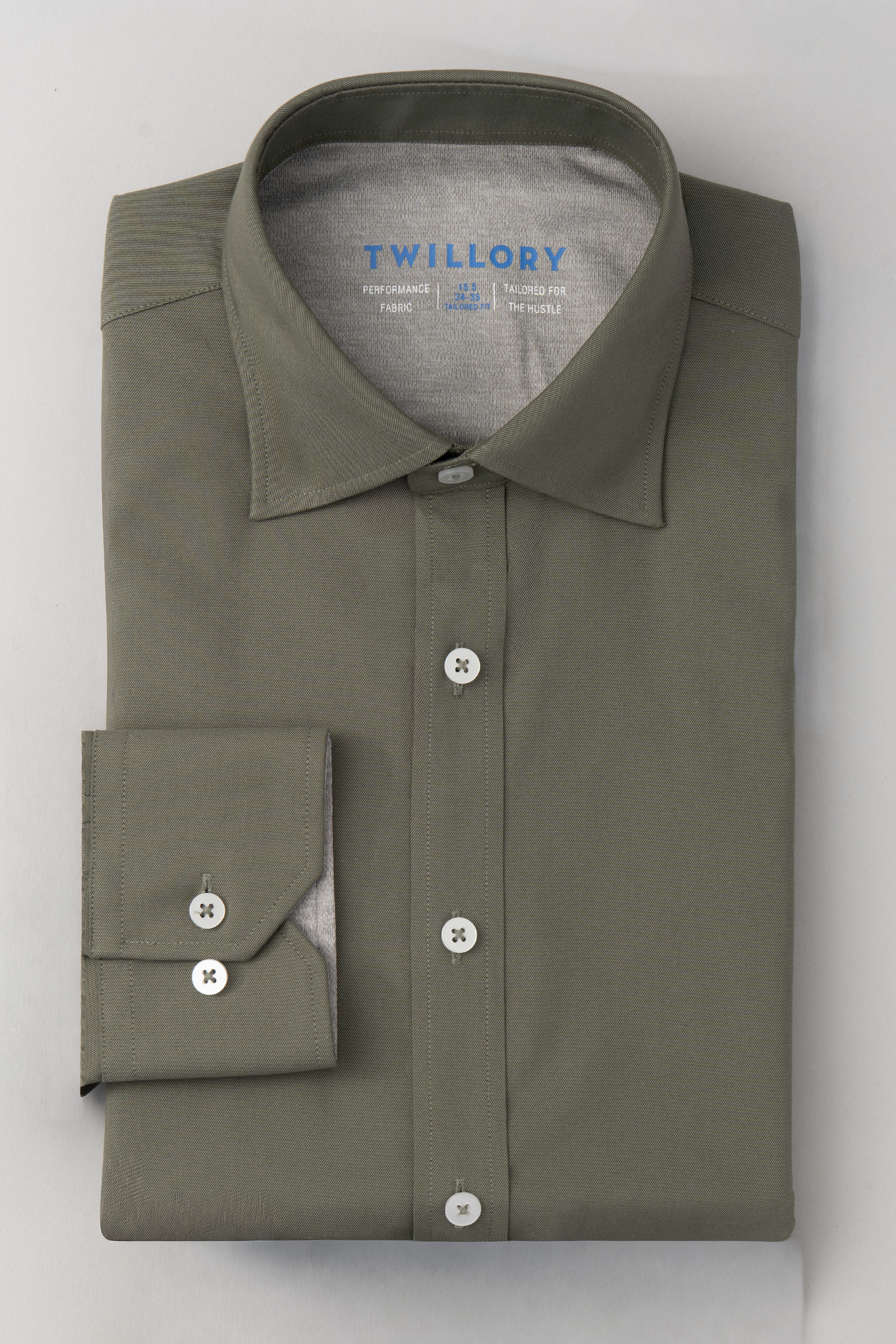 The Twillory Leader Solid // Olive is a neatly folded, long-sleeved performance shirt in olive green with white buttons, a stiff collar, blue Twillory branding inside the collar, and 4-way stretch. Displayed on a flat white surface.
