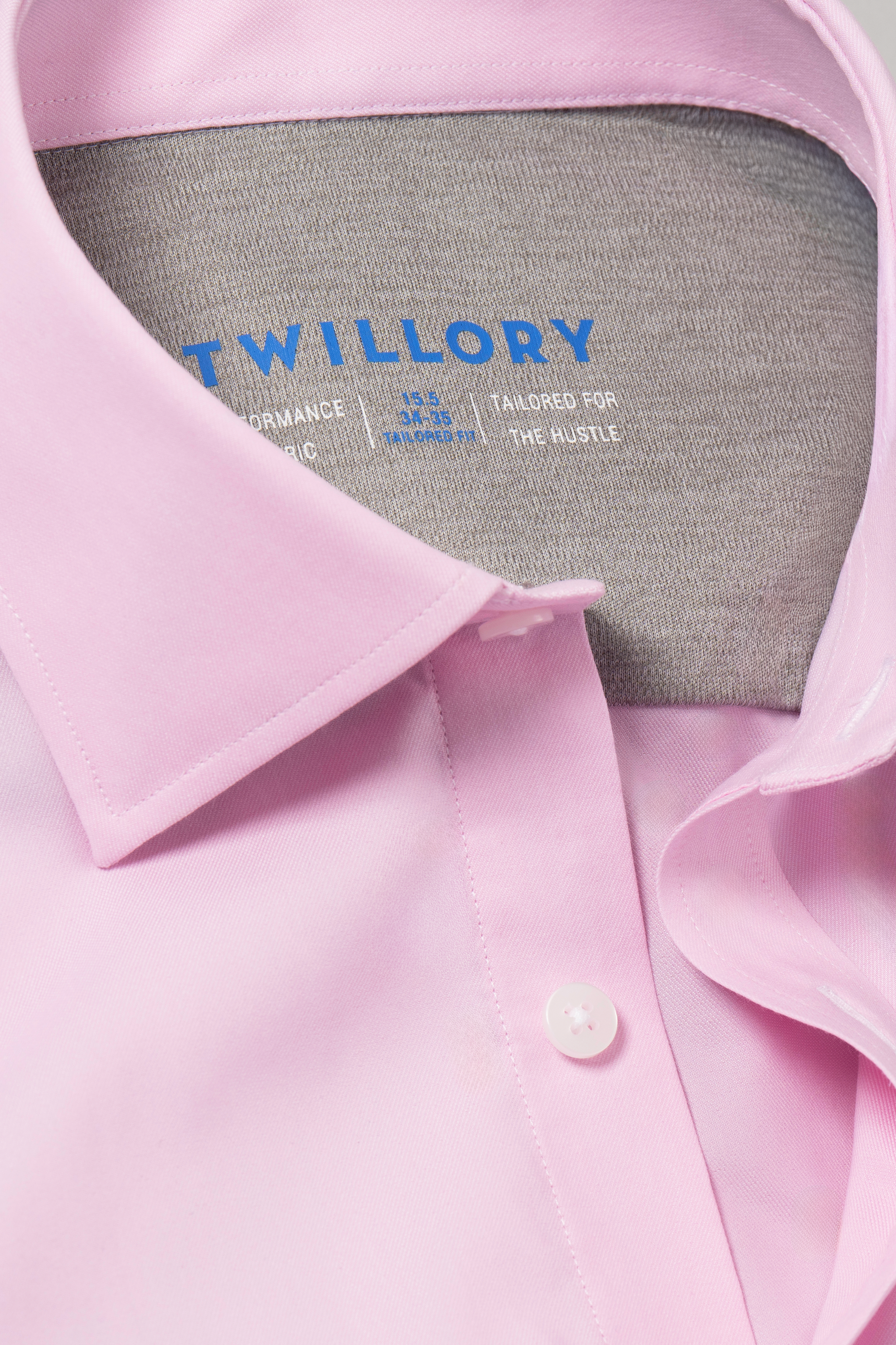 Close-up of the Twillory Leader Solid // Pink performance shirt featuring 4-way stretch, white buttons, a light gray contrasting inner collar, and a blue WILLORY label.
