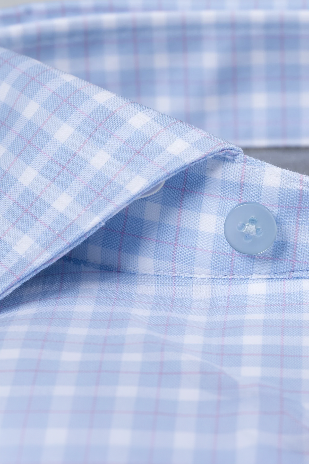 Close-up of Twillory's Leader Plaid // Sky Blue shirt, featuring light blue and white checks with subtle red lines. Shows the collar and a blue button, highlighting crisp texture, neat stitching, and moisture-wicking comfort.