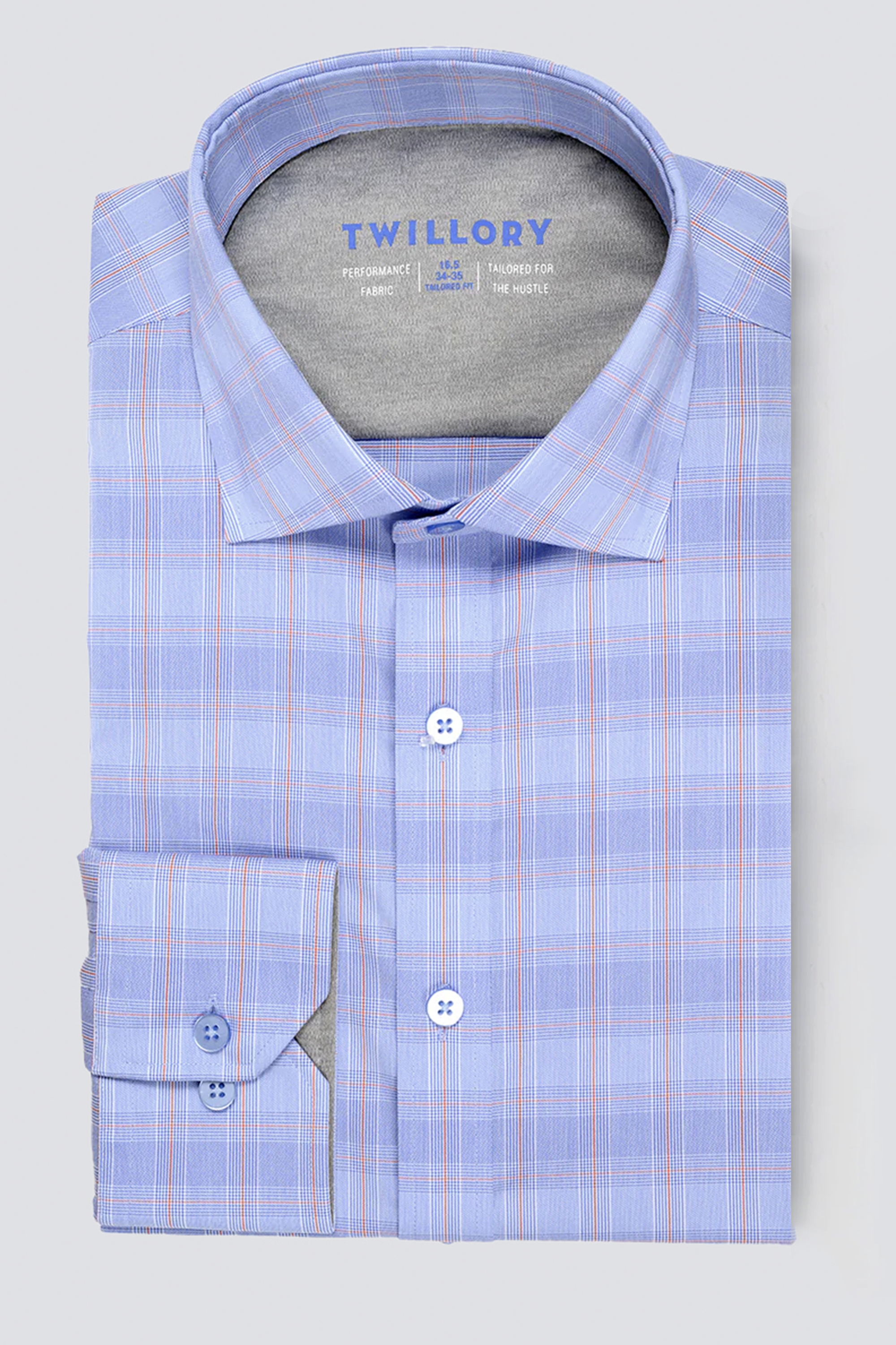 A neatly folded Twillory Leader Plaid // Blue Prince of Wales shirt with a subtle blue plaid pattern and faint orange lines, pointed collar, buttoned cuffs, Non Iron fabric, displayed on a plain light gray background.