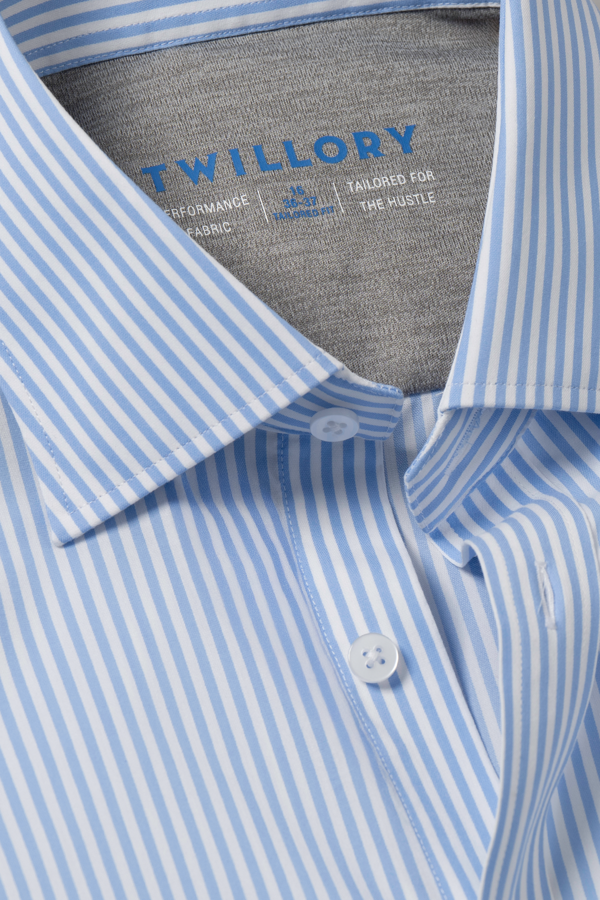 Close-up of Twillory’s Leader Stripe // Sky shirt, neatly folded. Features blue and white vertical stripes, pointed collar, white buttons, and inner branding on gray lining. Moisture-wicking fabric ensures all-day comfort.