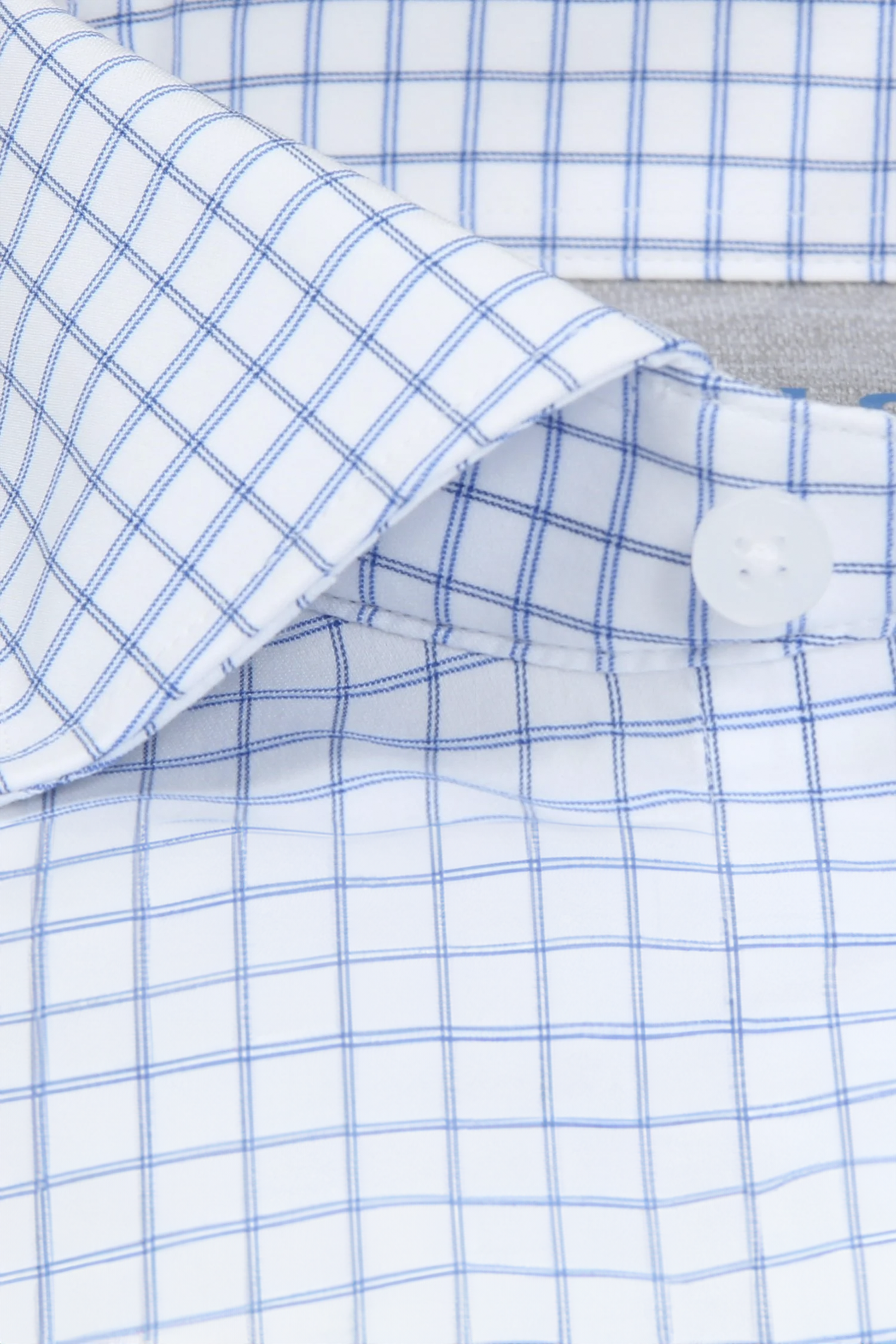 Close-up of Twillory's Leader Windowpane // Blue: a white collared performance shirt with a blue grid plaid, crisp seams, white button, and advanced 4-way stretch for a clean, formal look and superior comfort.