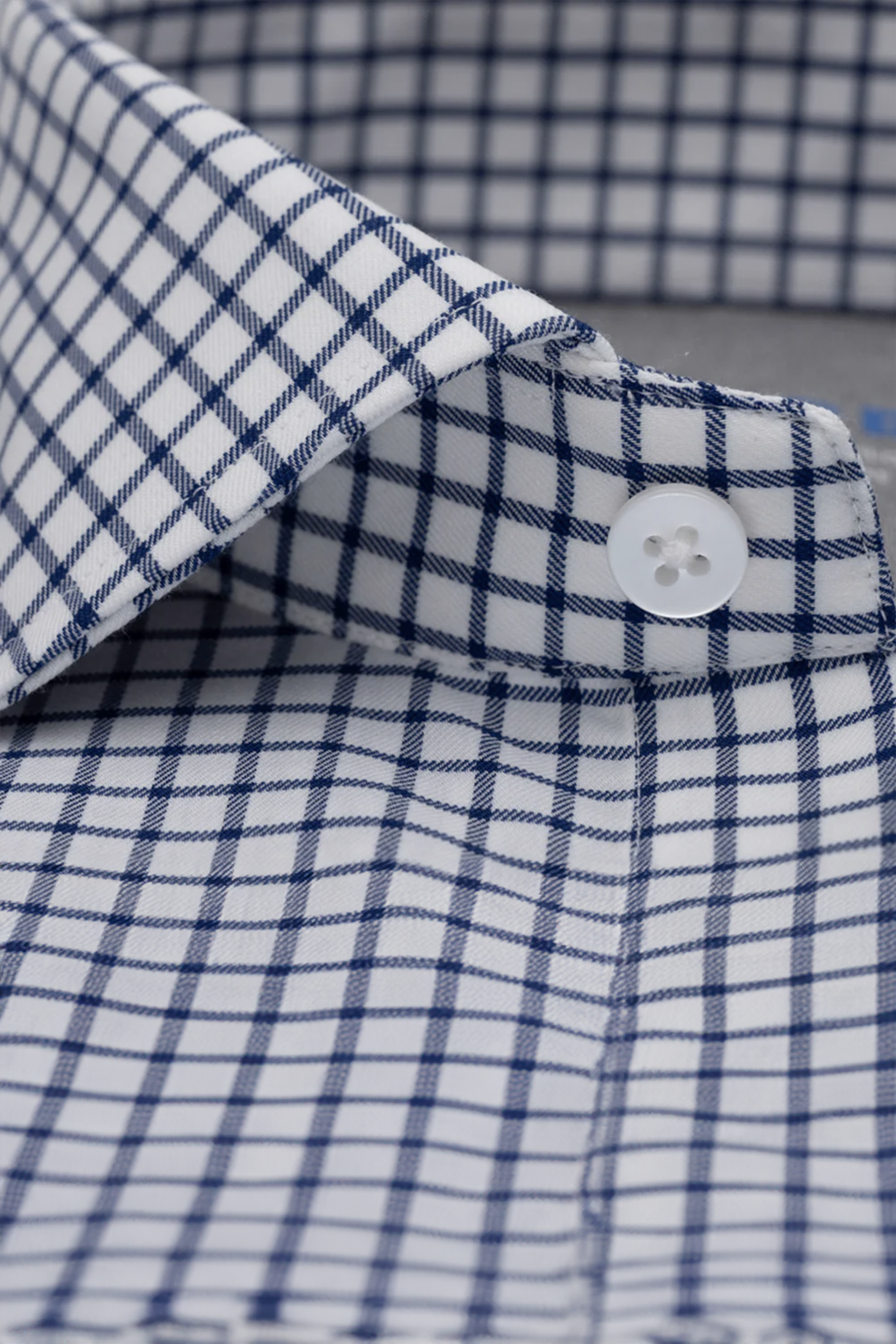 Close-up of Twillory's Leader Windowpane // Navy shirt, featuring a white base with a navy grid check. Image highlights the crisp collar, top button, neat stitching, and smooth 4-way stretch fabric for comfort.