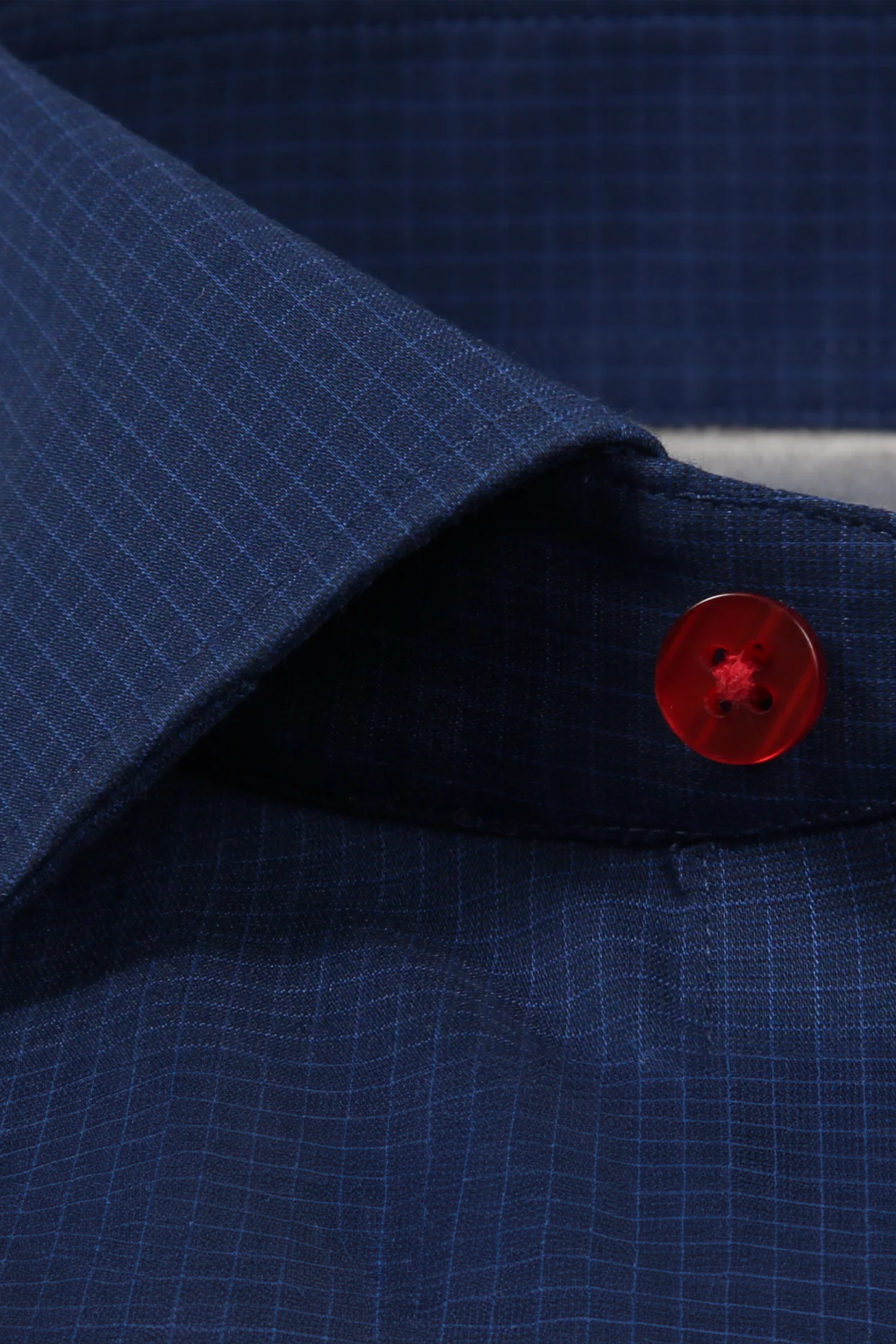 Close-up of the Twillory Leader Windowpane // Navy Red Contrast shirt, featuring a subtle grid pattern, pointed collar, and standout red button. Moisture-wicking fabric and 4-way stretch provide comfort; visible stitching adds detail.