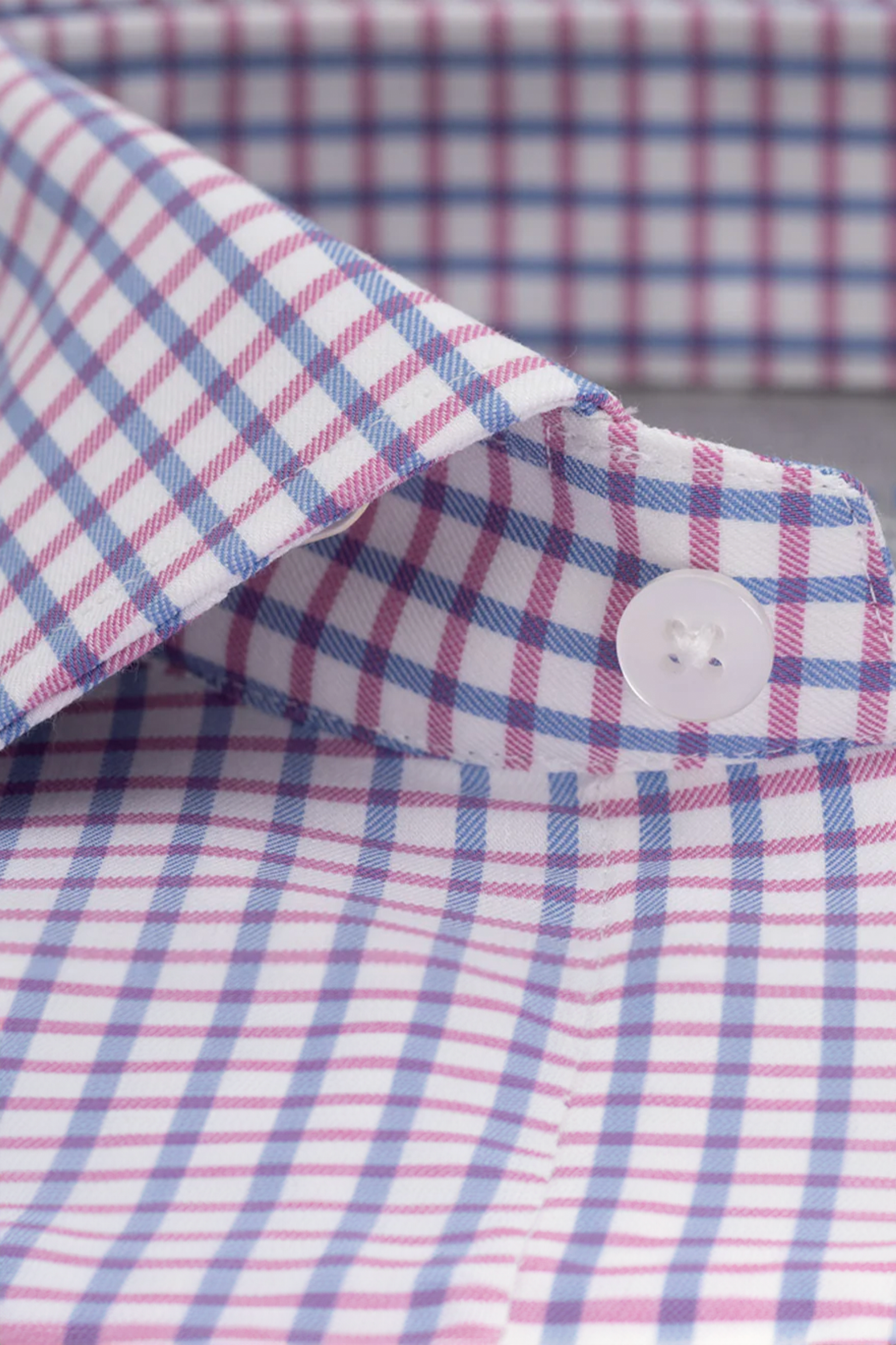Close-up of Twillory's Leader Windowpane // Pink Blue performance shirt, featuring a crisp checkered pattern in white, light blue, and pink. Image highlights the collar and top button; advanced moisture wicking keeps you comfortable all day.