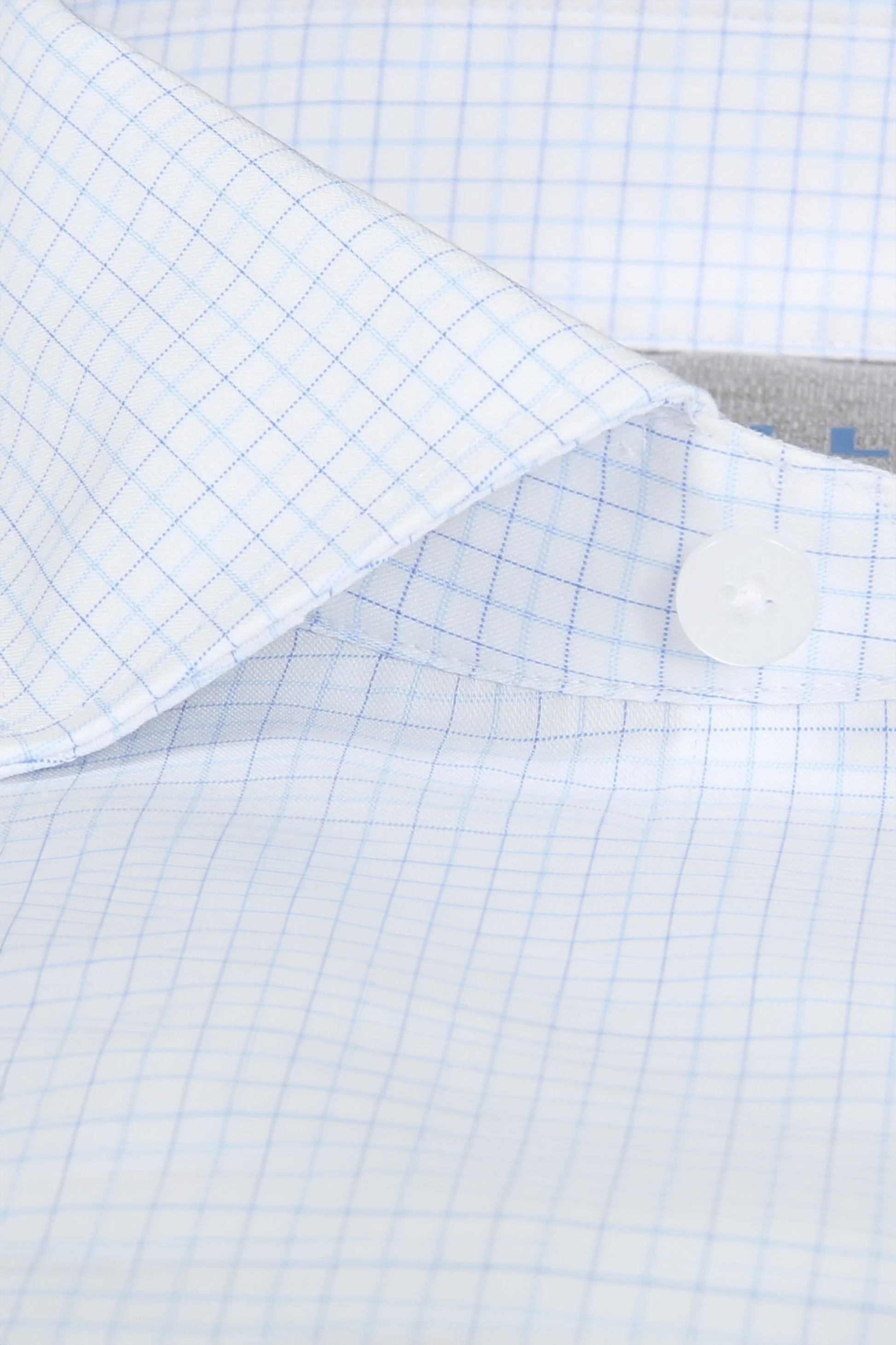Close-up of Twillory's Leader Windowpane // Sky Blue shirt, highlighting the collar, white button, and placket. Non-iron fabric features a fine sky blue grid pattern on a white background.