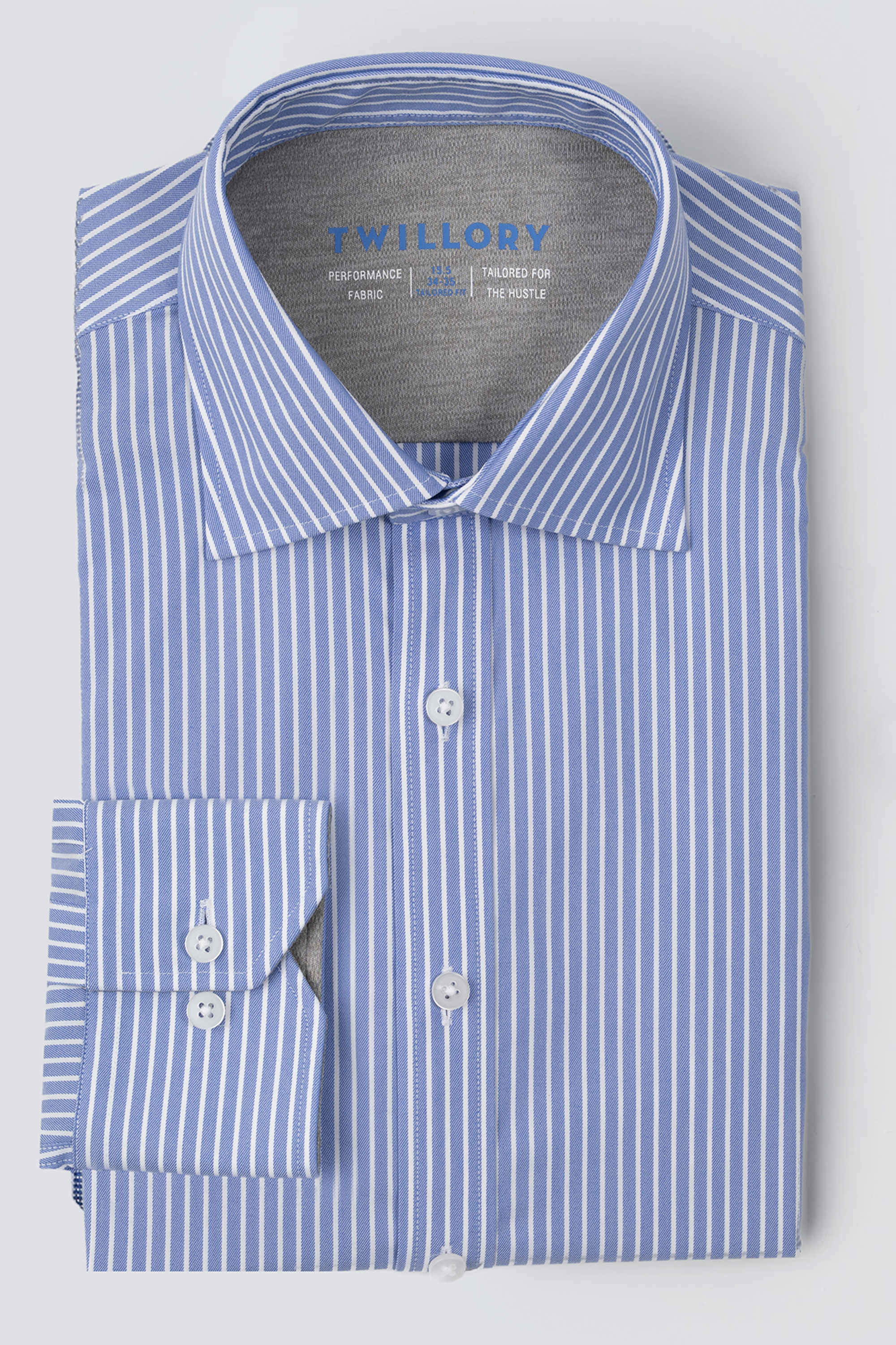 A neatly folded Twillory Leader Stripe // Mini Blue Performance Shirt with blue-and-white vertical stripes, white buttons, a classic collar with visible branding, and one cuff turned to show the inner lining is displayed.