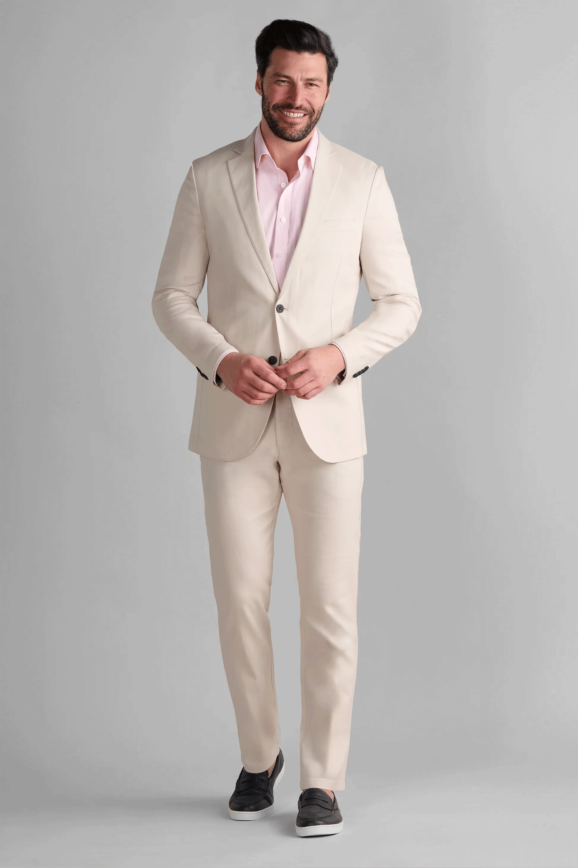 Man walking in a full Twillory Performance Linen Suit in Bone, demonstrating the flexible 4-way stretch and lightweight feel of the tailored blazer and pants. This non-iron suit is designed for comfort in warm climates, featuring moisture-wicking properties and a modern slim silhouette.