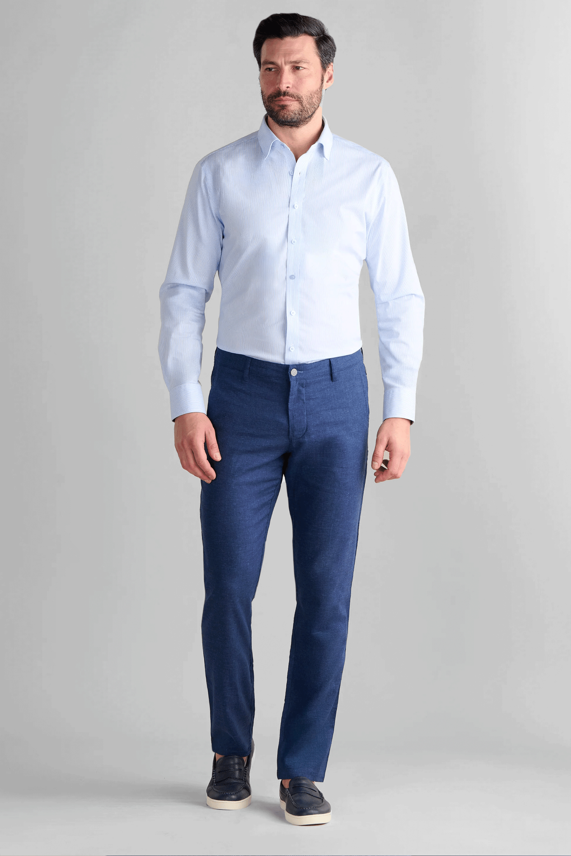 A man wearing Twillory Performance Linen Pants in Blue, featuring a tailored fit and breathable, wrinkle-resistant fabric. The outfit is styled with a light blue button-down shirt and navy leather loafers, highlighting the pants' non-iron texture and professional casual look.