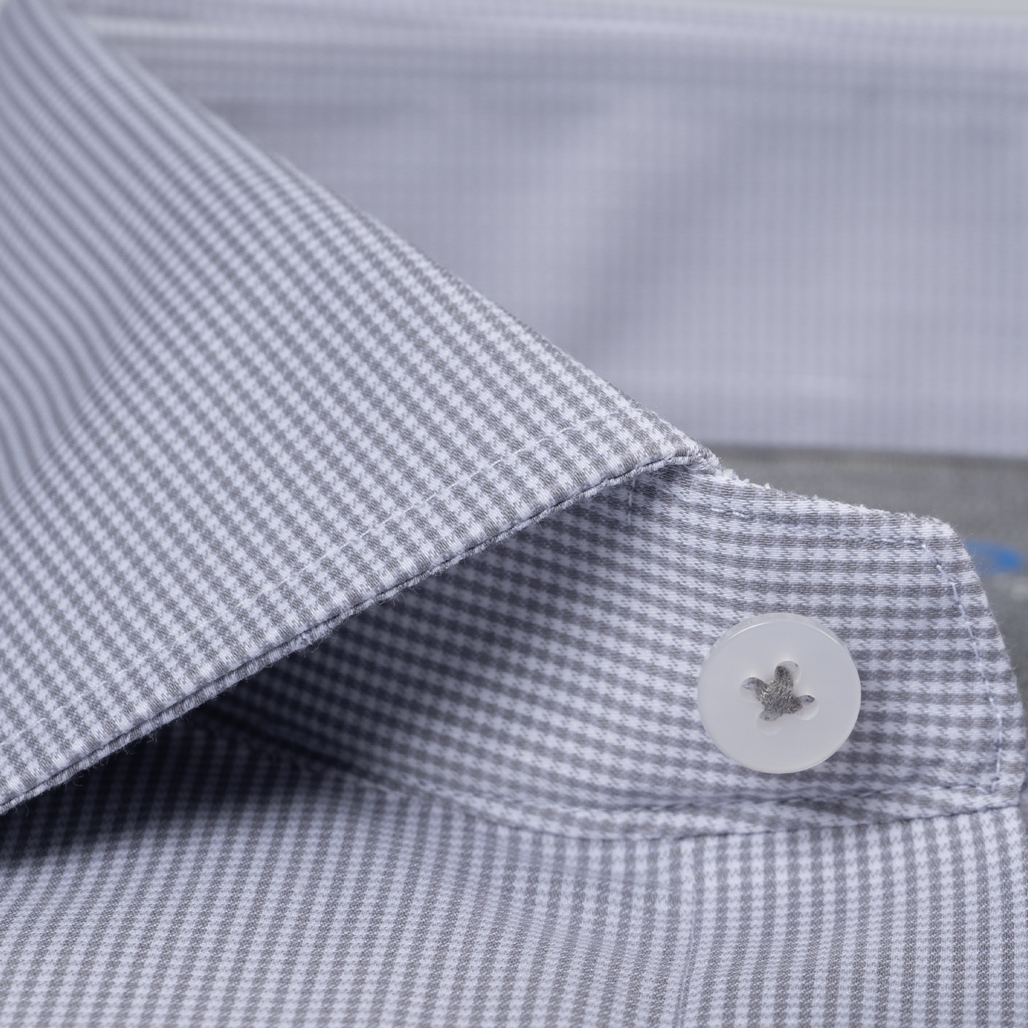 Close-up of the ADVANCER // Performance Grey Houndstooth shirt by Twillory: a non-iron, crisp performance fabric with clean stitching, gray and white houndstooth pattern, and a white button sewn with gray thread for a sharp look.