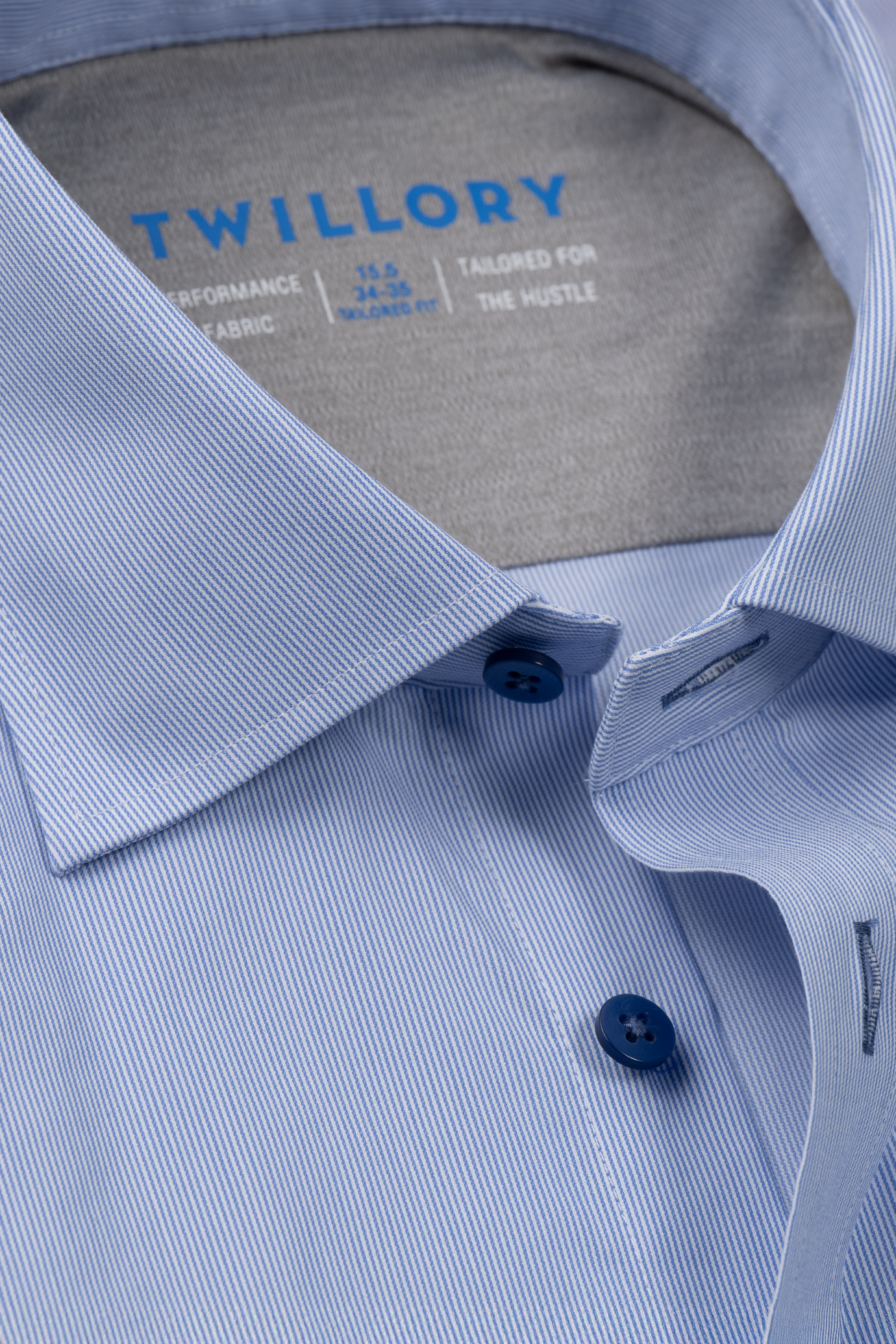 Close-up of the Twillory Leader Stripe // Micro Blue shirt, neatly folded with fine pinstripes, dark blue buttons, and visible collar. Features 4-way stretch, moisture-wicking fabric, and tailored fit. "TWILLORY" label shown on a grey background.