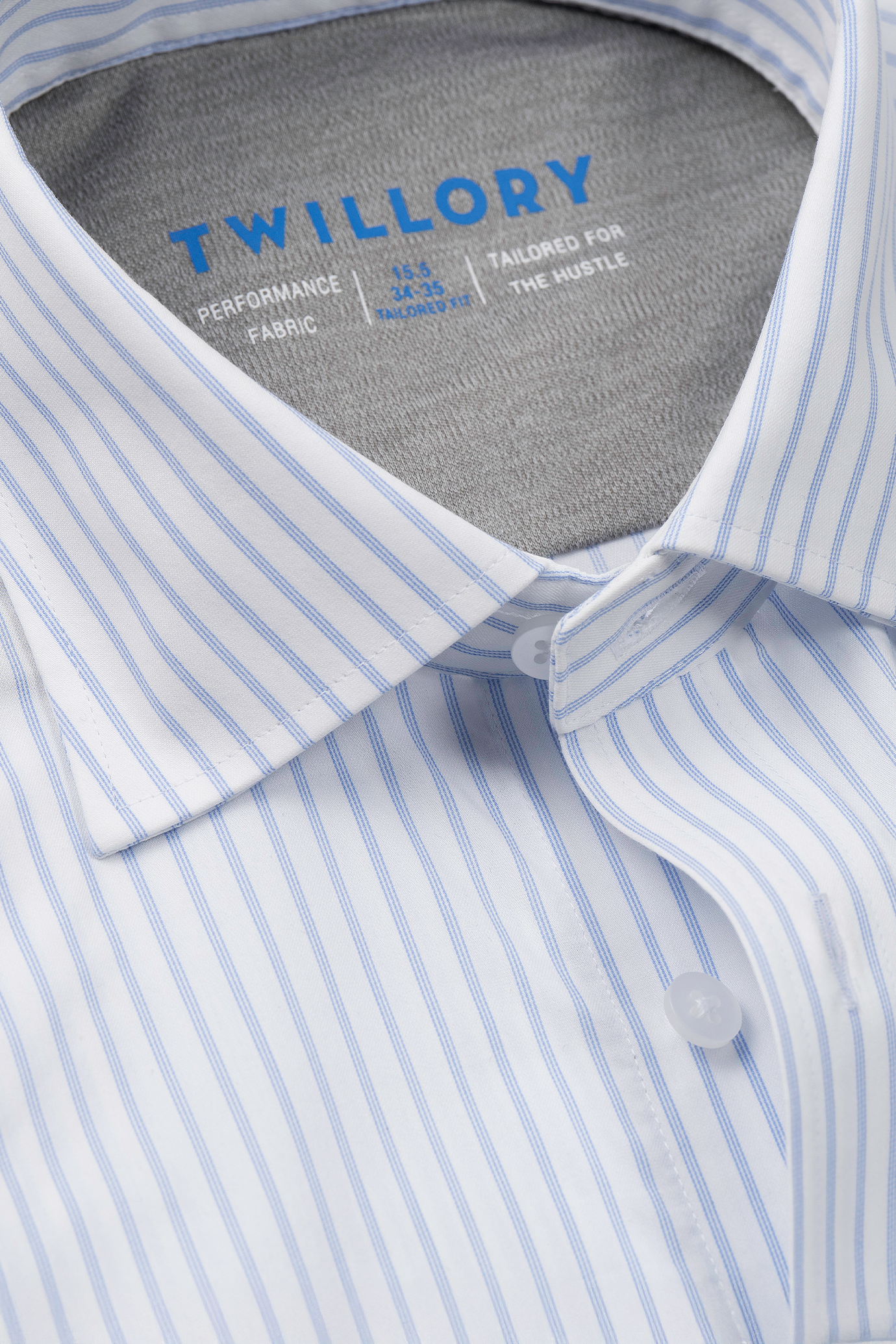 A close-up of a neatly folded Twillory Leader Stripe // Thick White shirt, featuring button-down collar and blue branding, showcases its tailored fit and moisture-wicking performance.