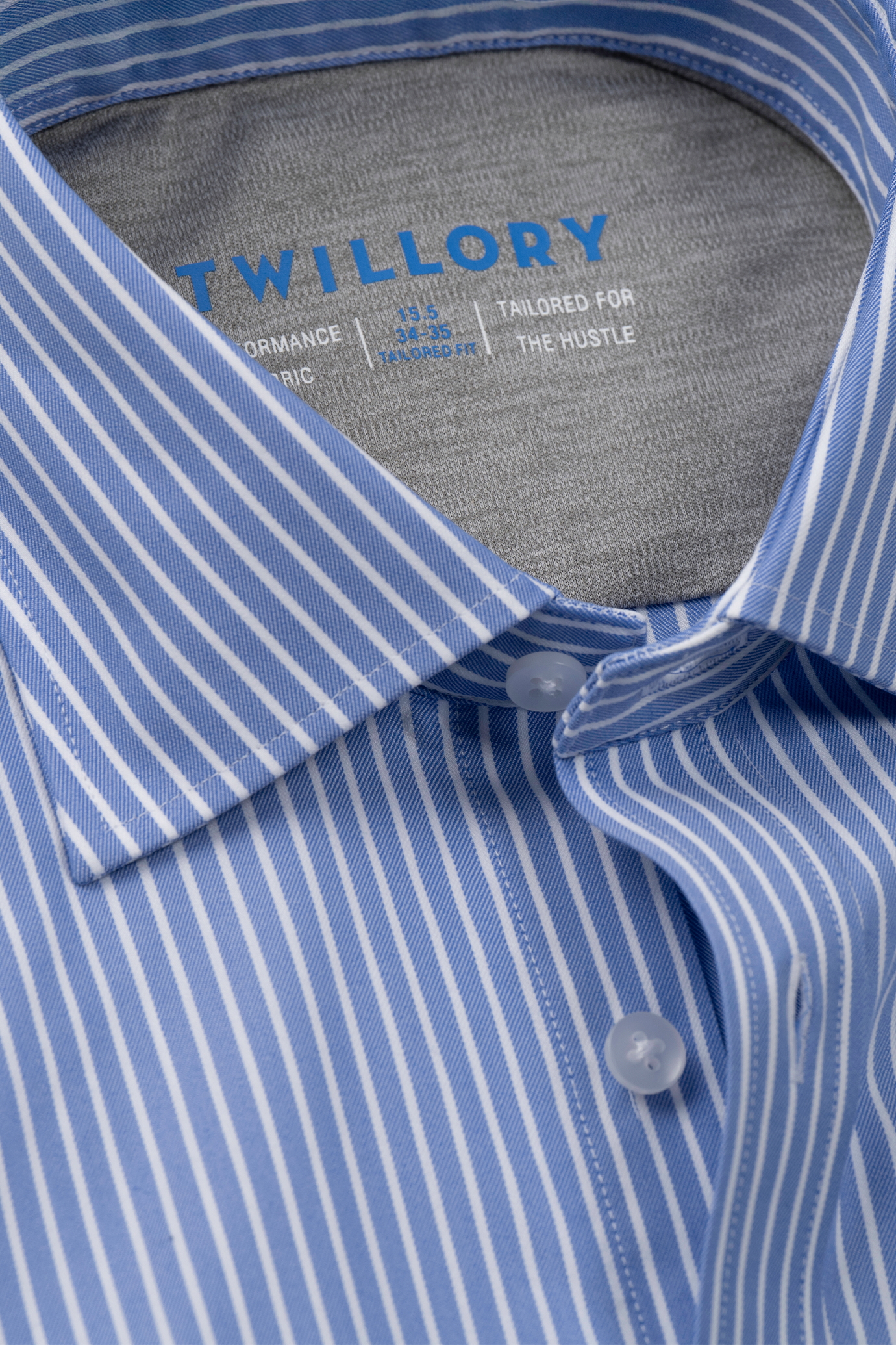 Close-up of the Twillory Leader Stripe // Mini Blue Performance Shirt, featuring blue and white vertical stripes, spread collar, two white buttons, visible inner label, and moisture-wicking fabric for all-day comfort.
