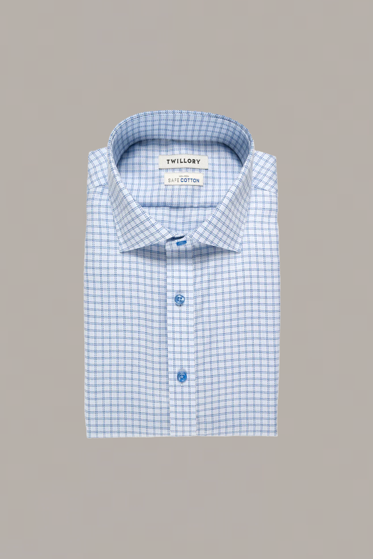 A folded Twillory Non-Iron Blue Windowpane Twill shirt with long sleeves and a blue plaid pattern is displayed on a plain gray background, featuring a visible collar, two blue buttons, and a Twillory SafeCotton label inside.