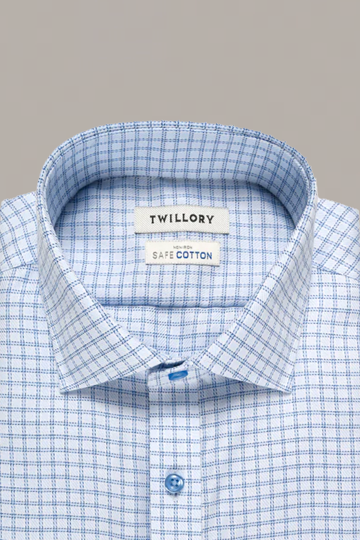 A neatly folded Twillory Non-Iron Blue Windowpane Twill shirt features a button-down collar, blue buttons, and fine blue check patterns on white. The inner label reads TWILLORY over SAFE COTTON.