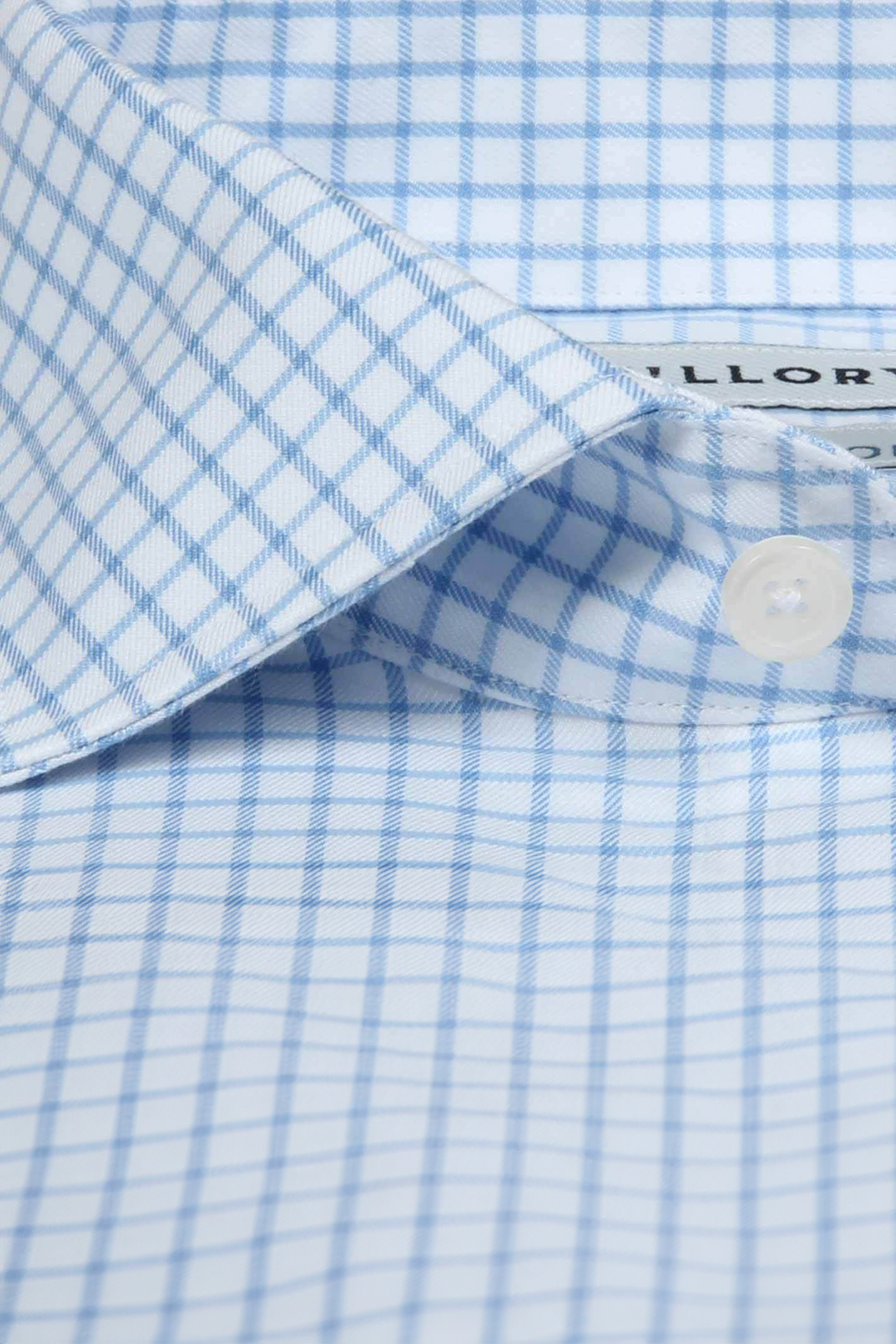 Close-up of a Twillory Non-Iron Sky Windowpane shirt’s pointed collar, featuring a blue and white check pattern, white button, inner label detail, and neatly pressed stretch cotton fabric.
