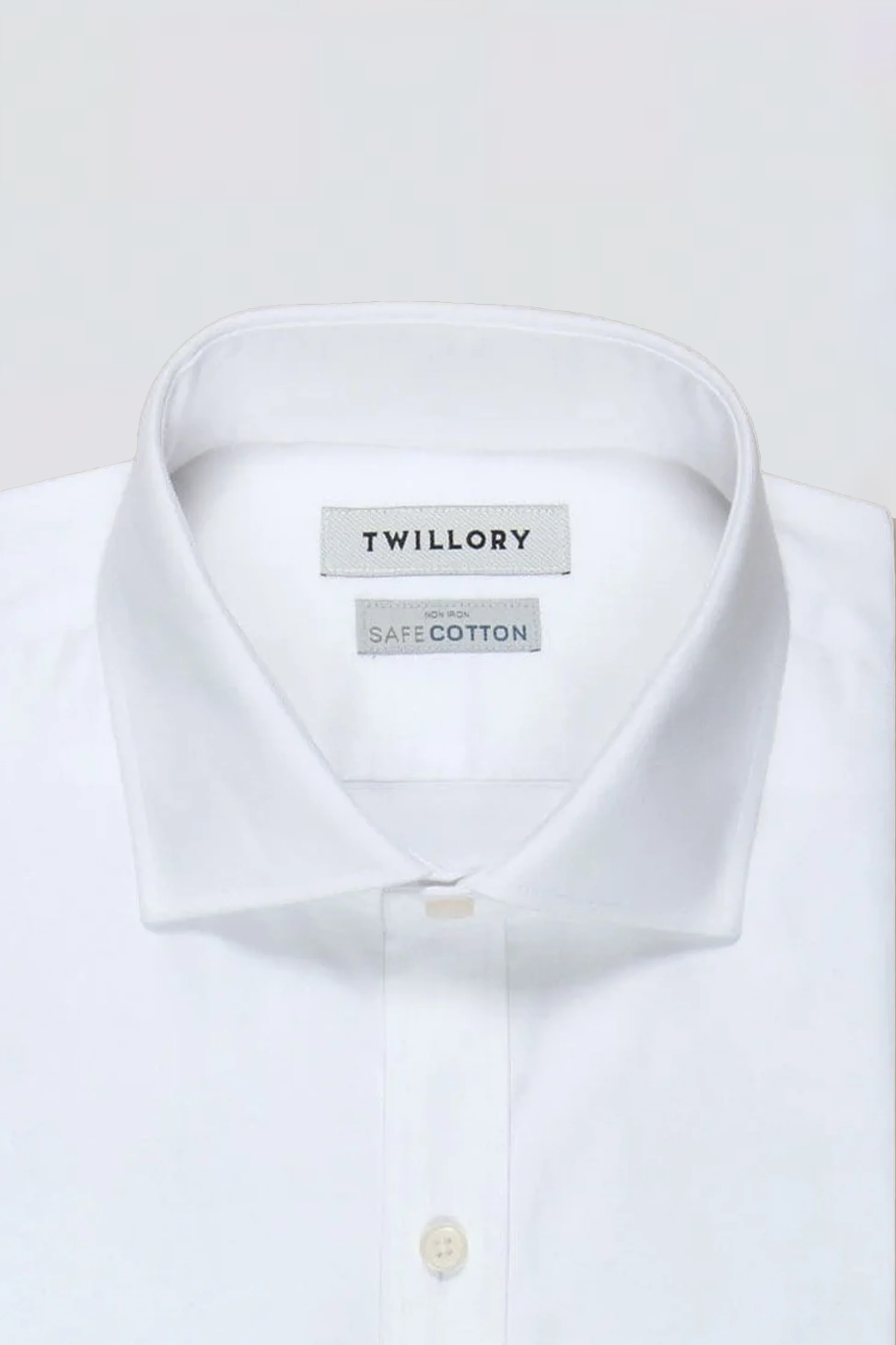 A neatly folded Non-Iron White Twill dress shirt by Twillory is shown. The pointed collar reveals tags for "Twillory" and "SafeCotton." Made from hyperbreathable, non-iron fabric, the top button is unfastened to show the placket.