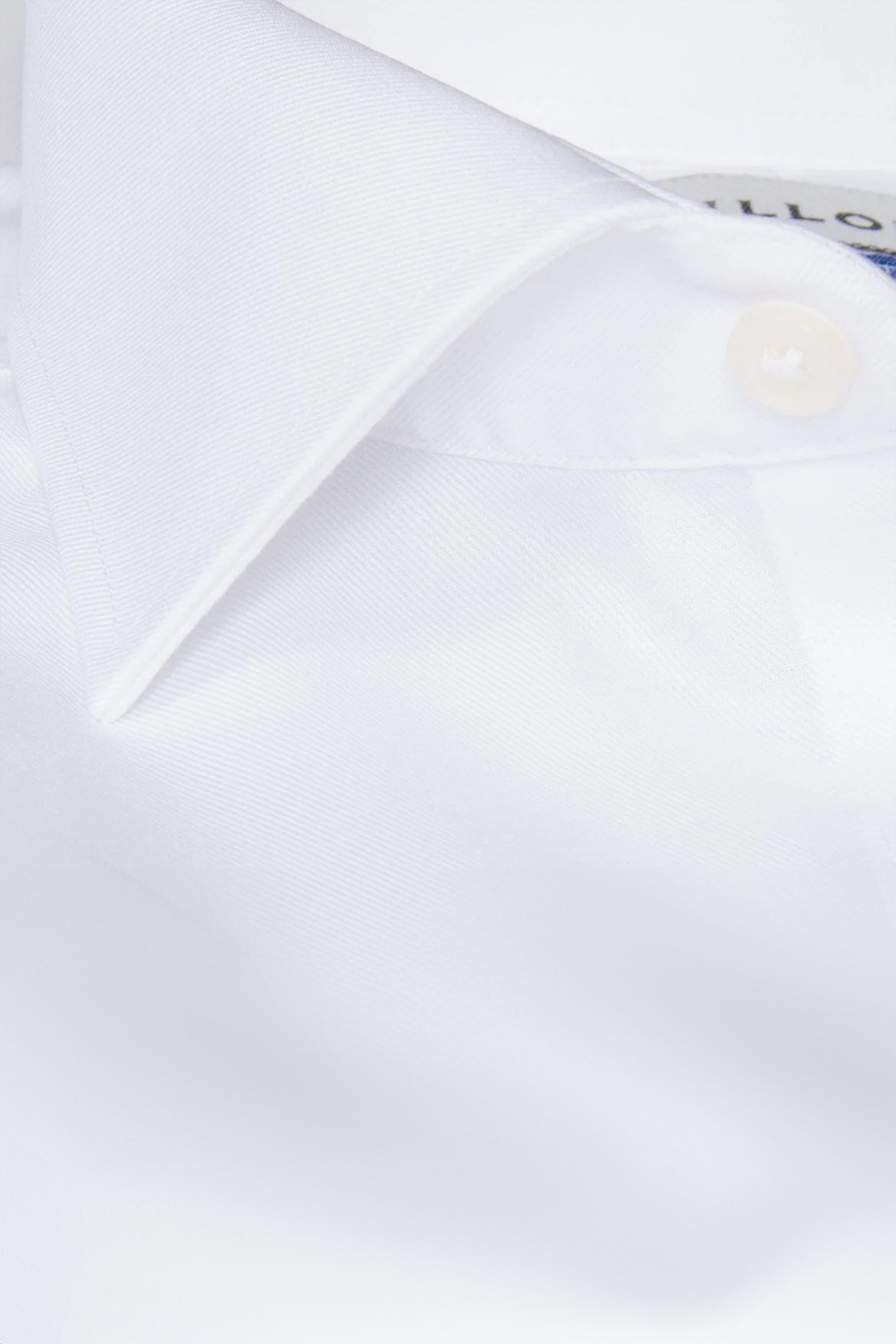 Close-up of Twillory's Non-Iron White Twill shirt showing its smooth, crisp fabric, pointed collar, part of a button, visible stitching details, and label—highlighting its professional look and easy-care material.