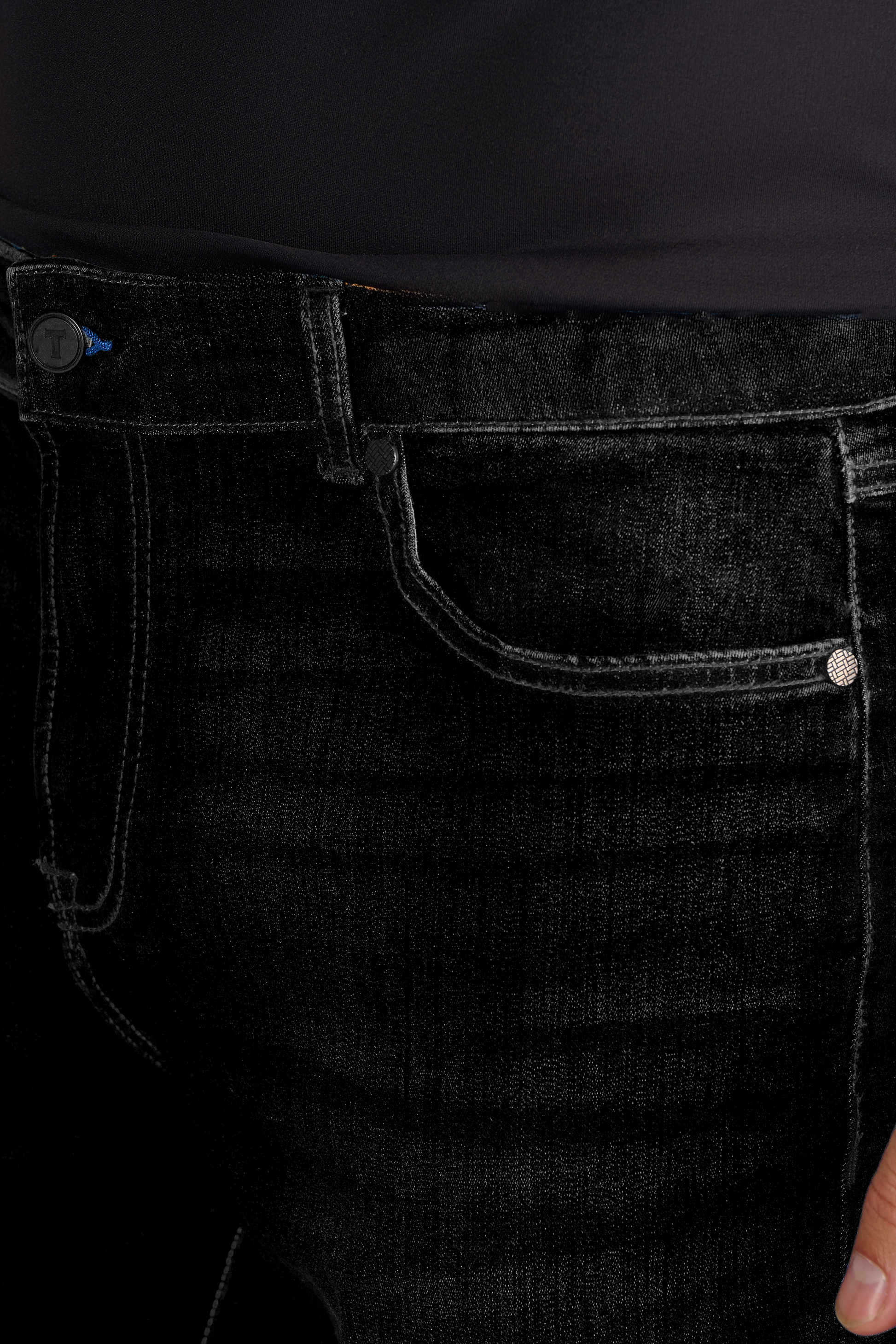 Close-up of a person wearing Twillory Performance Denim // PURE BLACK jeans and a dark top, highlighting the waistband, front pocket with metallic rivet, button, visible stitching, and the denim’s unique texture.