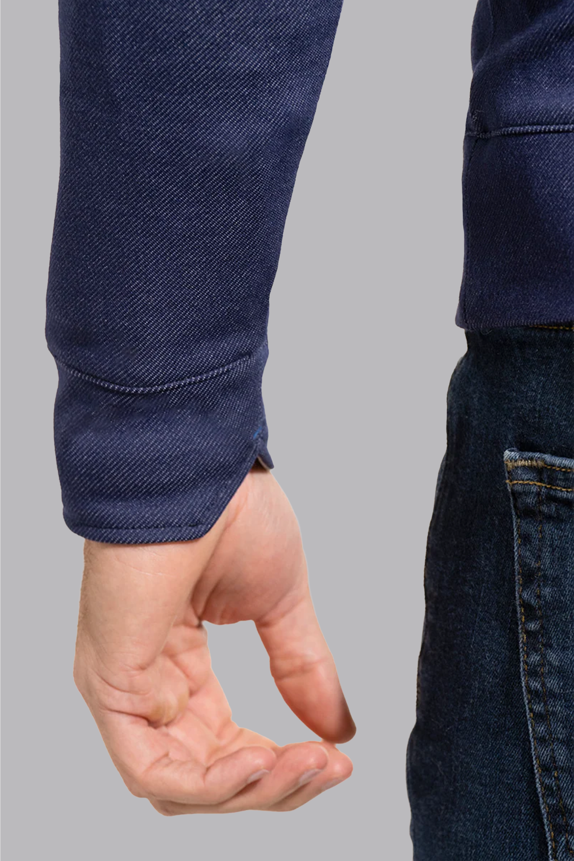 A close-up of a person’s left arm and hand against a grey background, wearing Twillory’s Performance Quarter Zip in Denim. The hand is relaxed, facing backward with partially curled fingers.