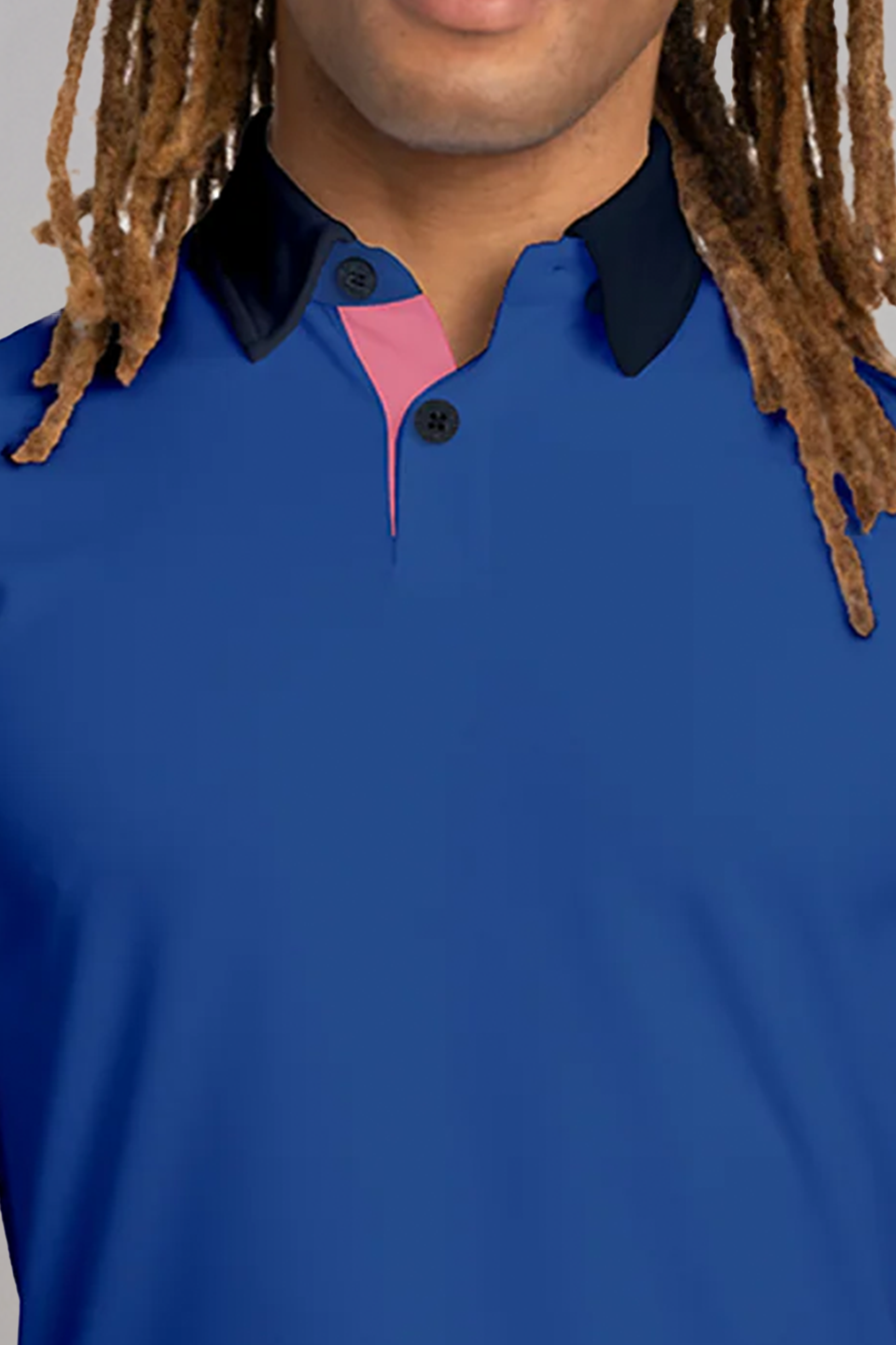 A person with long, light brown dreadlocks wears the Twillory Short Sleeve Polo Contrast // Blue Pink, featuring black collar tips, black buttons, and a pink inner placket. Only their lower face, neck, shoulders, and upper chest are visible against a plain gray background.