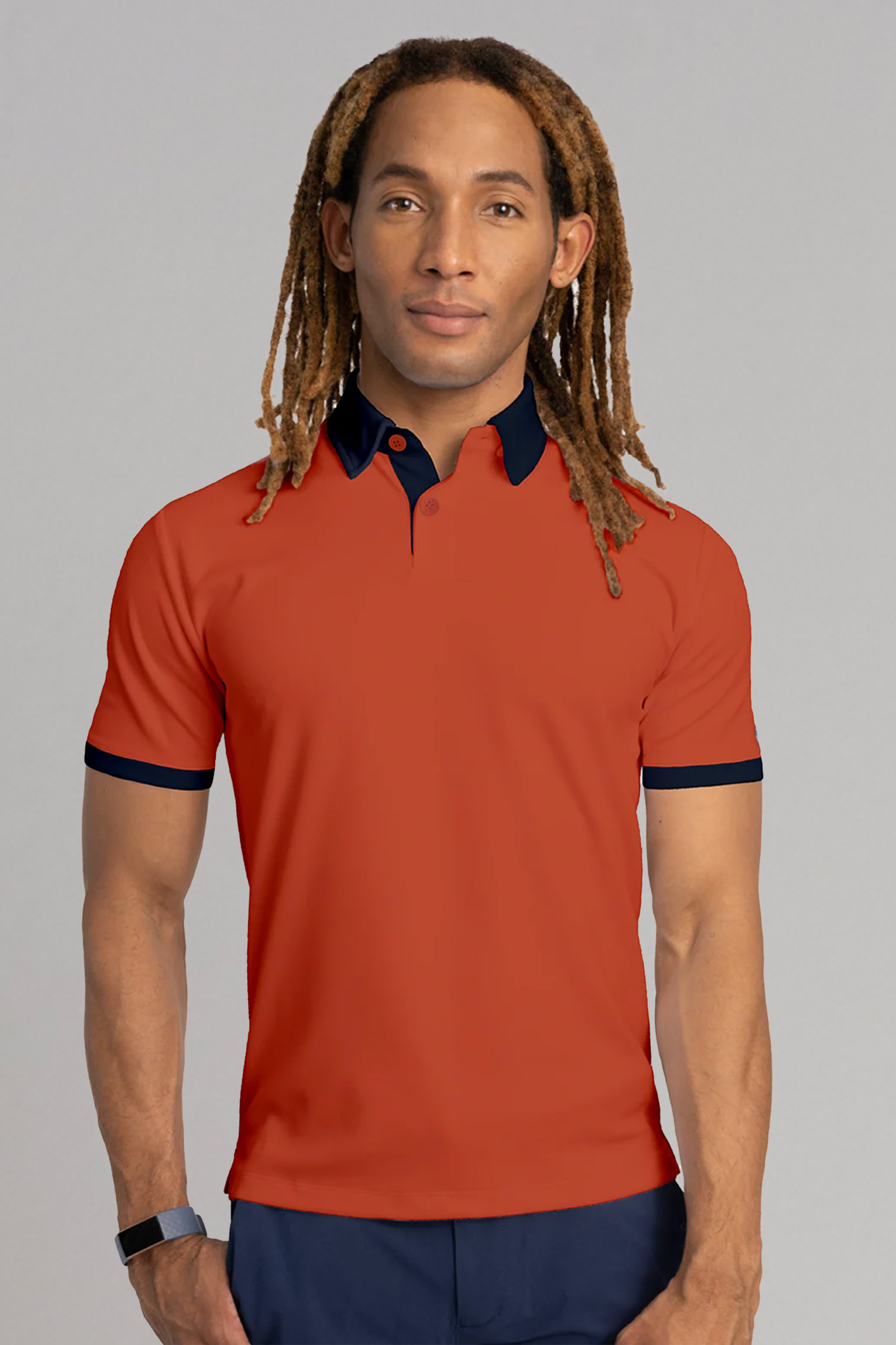 A person with light brown skin and long, light brown dreadlocks wears the Twillory Short Sleeve Polo Contrast in Orange Navy, featuring cooling tech for comfort. They face forward against a plain light gray background with a neutral expression.
