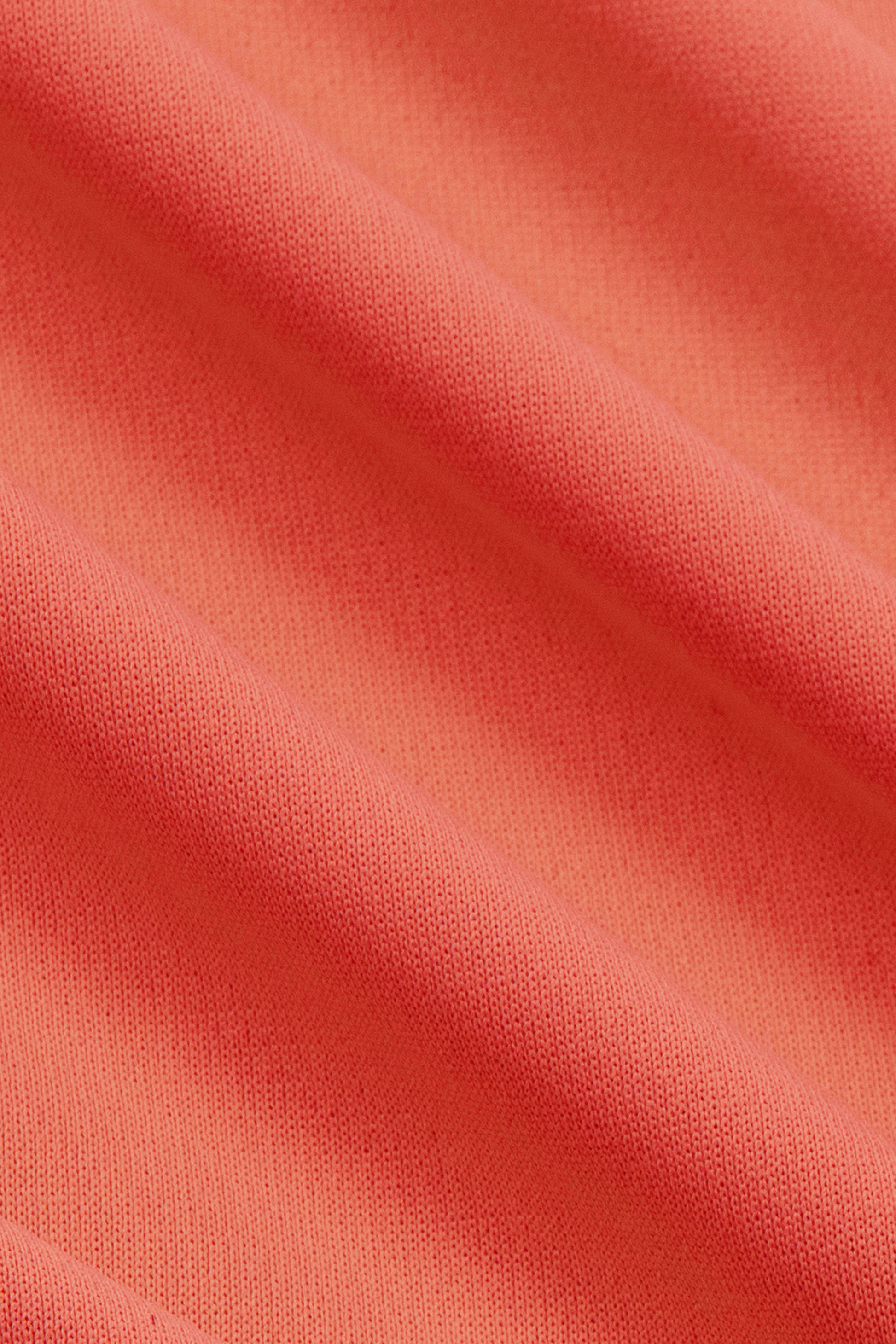 Close-up of the Twillory Short Sleeve Polo Solid in Salmon, showing its soft, thick knitted texture. Draped smoothly for a tailored fit, this moisture-wicking polo offers comfort and style.
