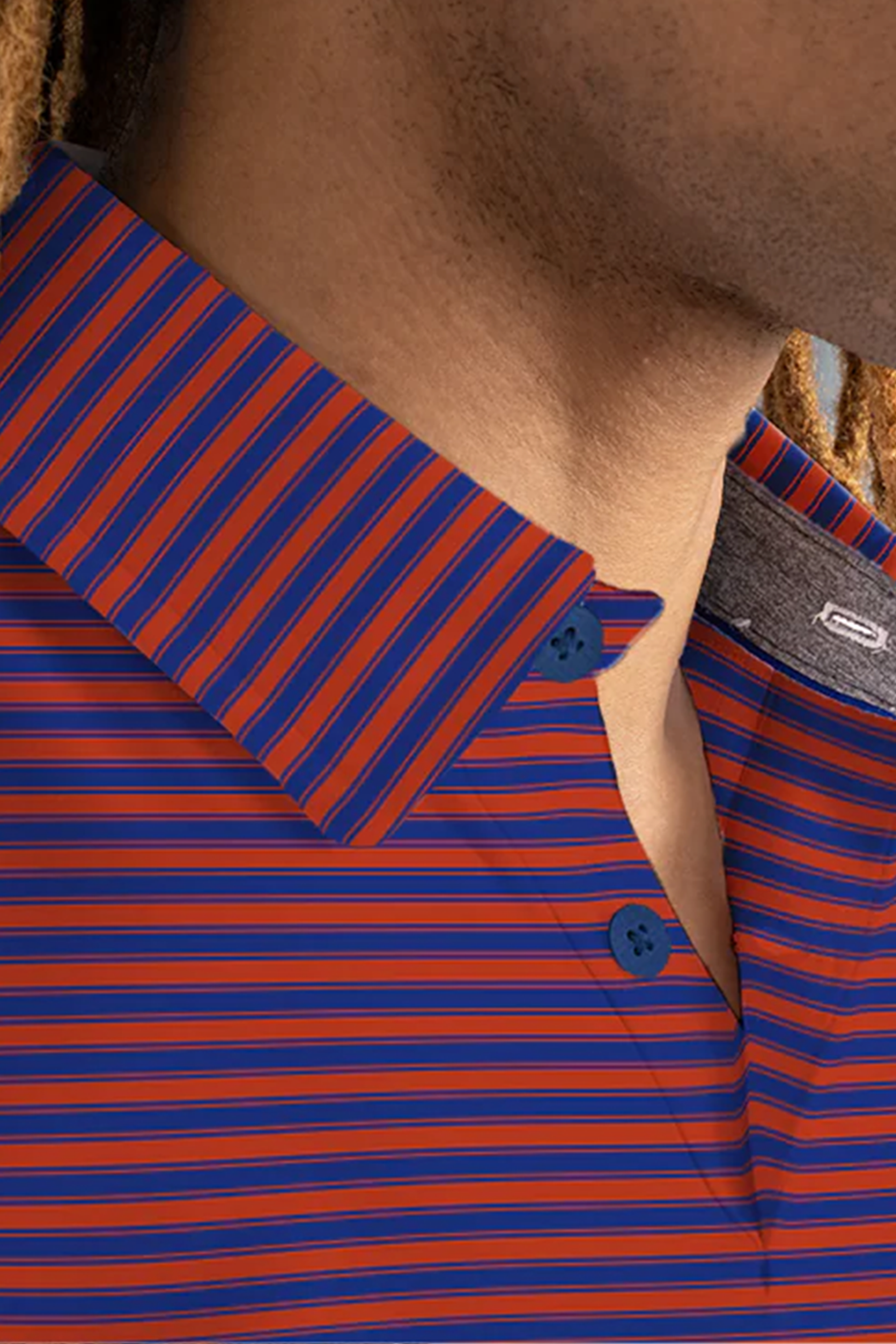 Close-up of a person wearing the Twillory Short Sleeve Polo Stripe // Red Blue, featuring blue and red horizontal stripes, two blue buttons at the collar, and moisture-wicking fabric. Dreadlocks are visible along their cheek.