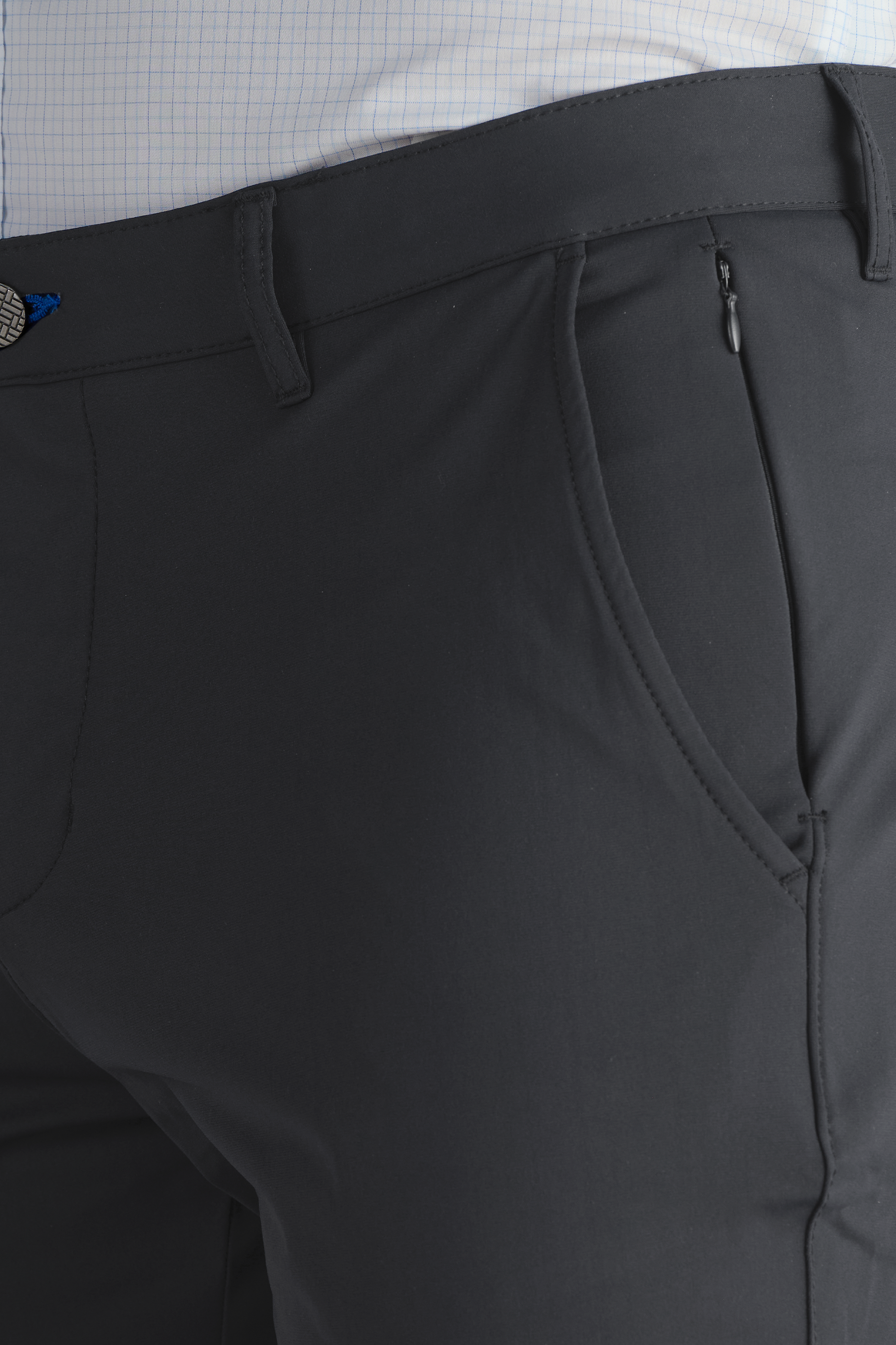 A close-up of a person wearing Twillory Performance Pants in SLATE GREY with front pocket, zipper, belt loops, and part of a tucked-in, light checkered shirt visible at the waistband.