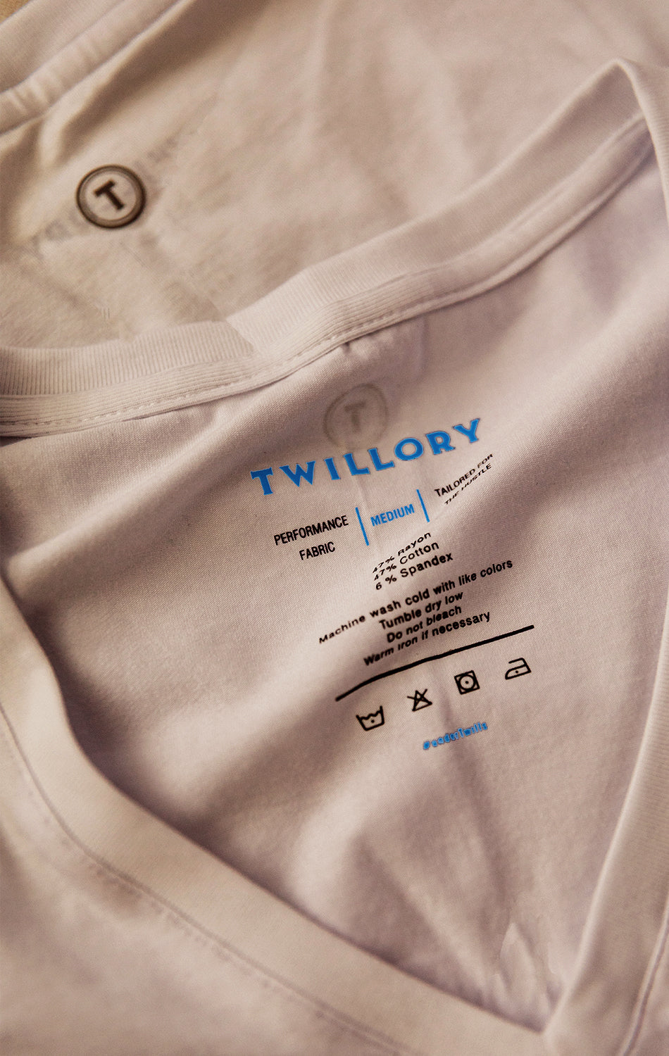 Close-up of the inside label on a Twillory Performance Undershirt 3 Pack // V Neck - Tonal in Medium shows the blue logo, care symbols, and washing instructions: machine wash cold with like colors and tumble dry low.